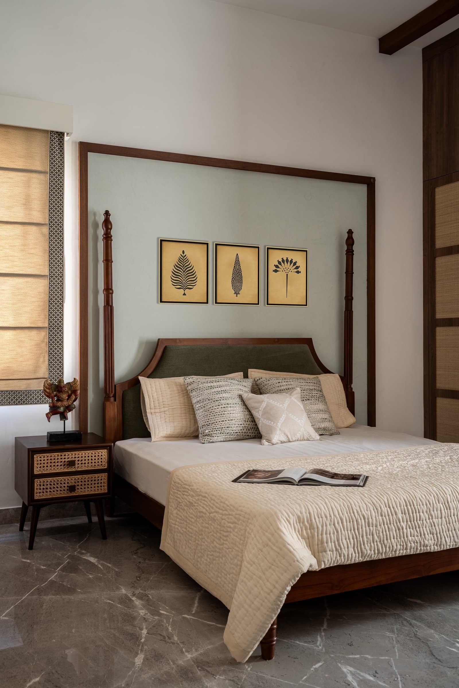 The master bedroom: a four-poster bed in dark teak set against a sage-tinted plaster panel, with three botanical prints at its centre