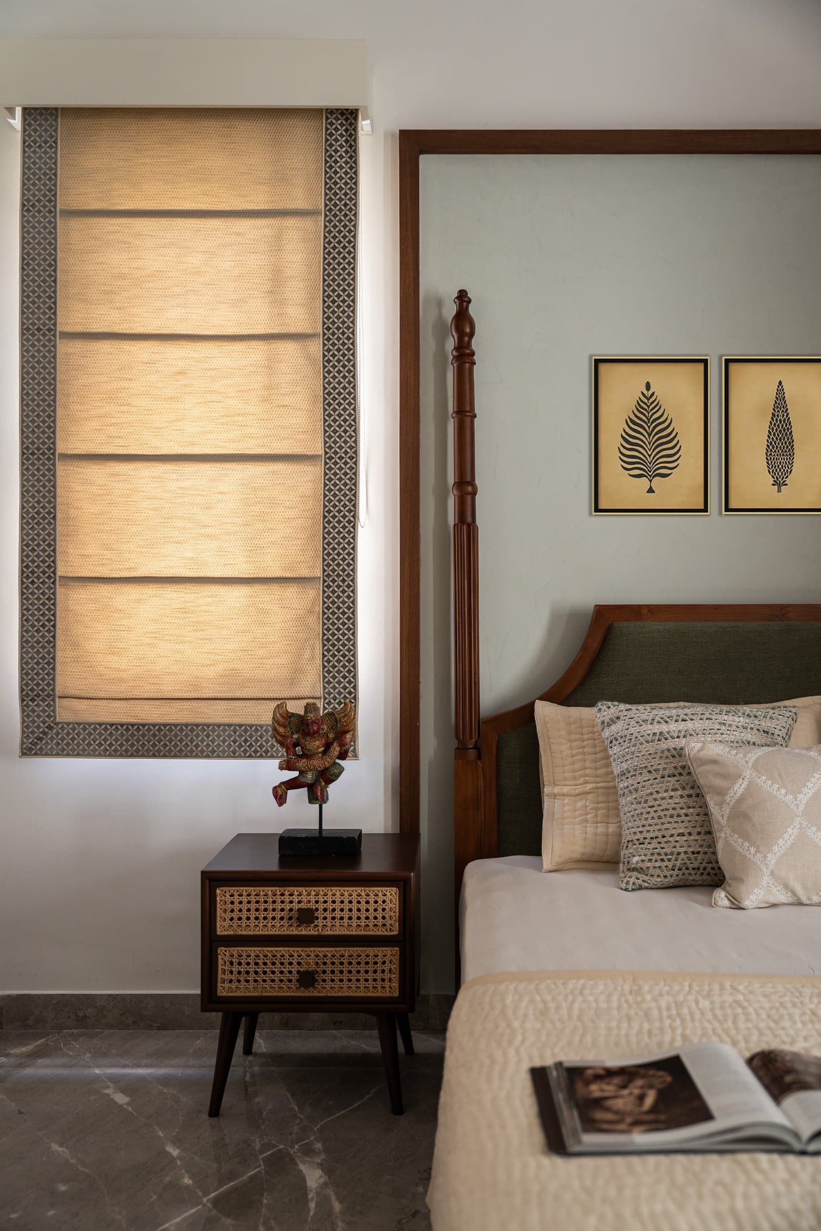 A cane-fronted nightstand and a patterned Roman blind soften the master bedroom's geometry