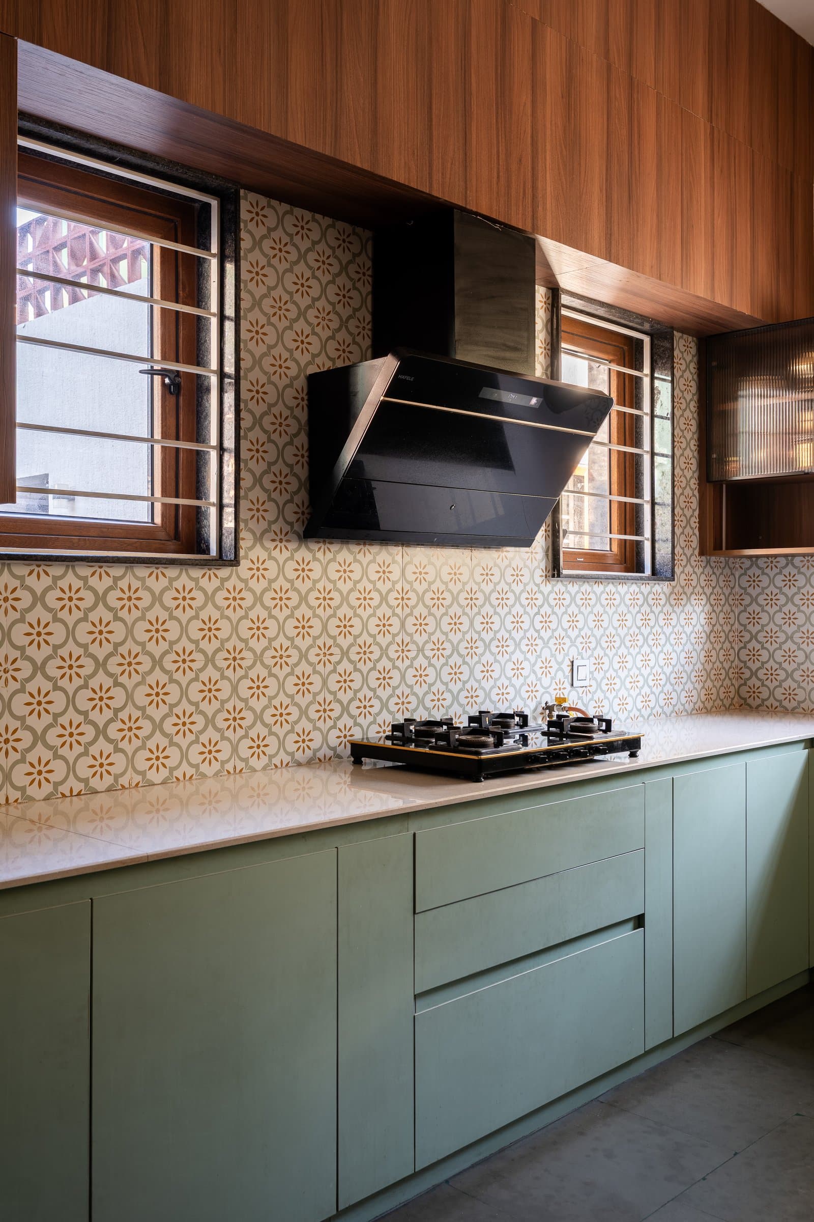 The kitchen, where sage cabinetry meets an encaustic backsplash of small ochre florals, restraint with a quiet point of view