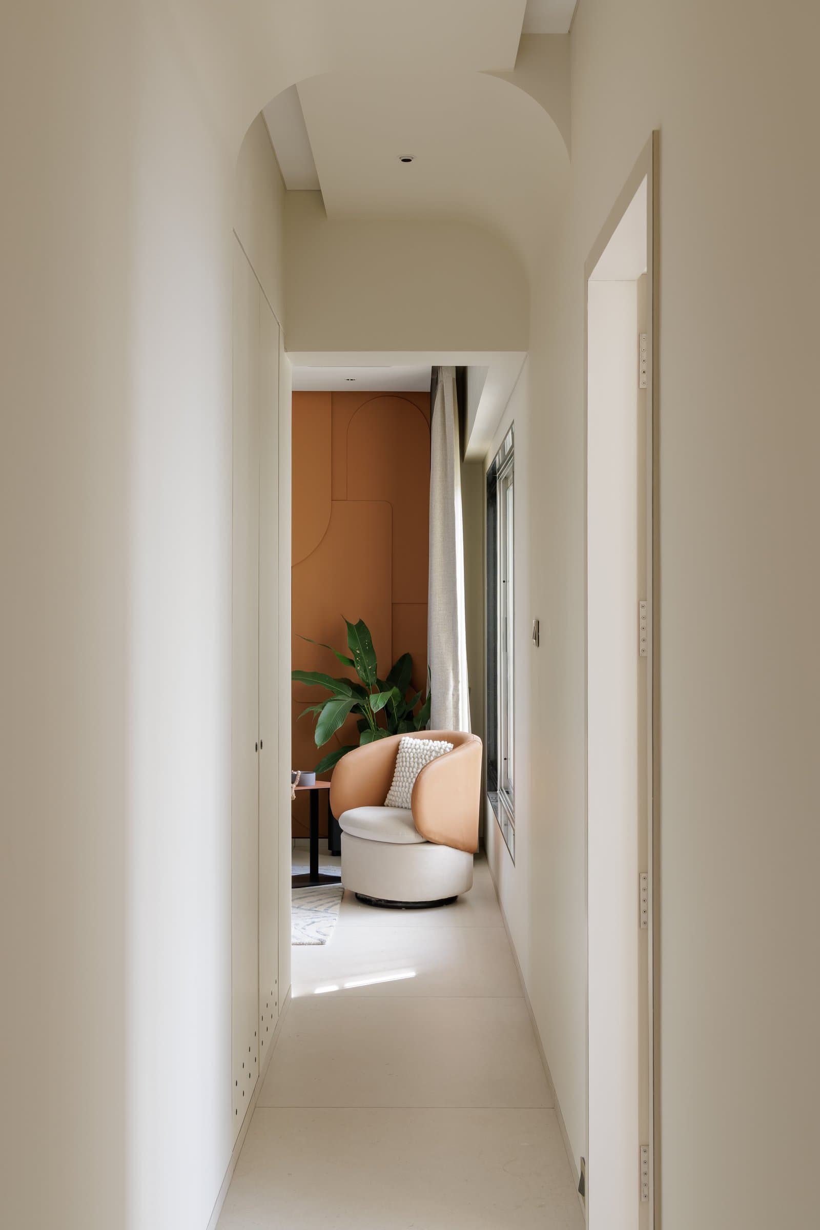 The connecting corridor, curved soffits overhead, the living room's sienna panel reasserting itself at the far end