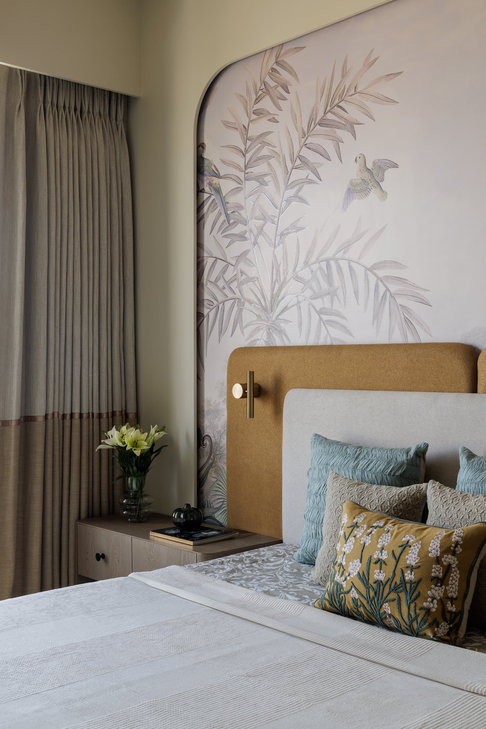 Seen from the side, the tan backrest carries brass sconces like jewellery on fabric