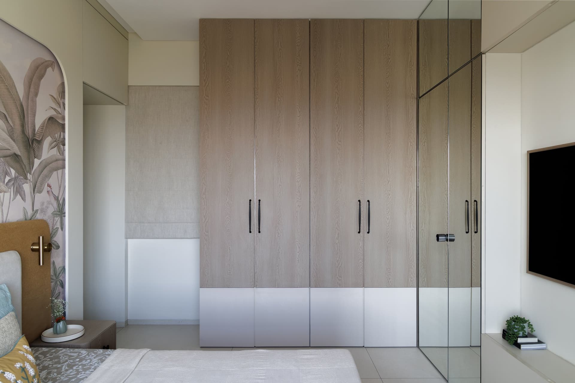 The opposite wall: full-height oak wardrobes whose restraint lets the mural remain the room's single drama