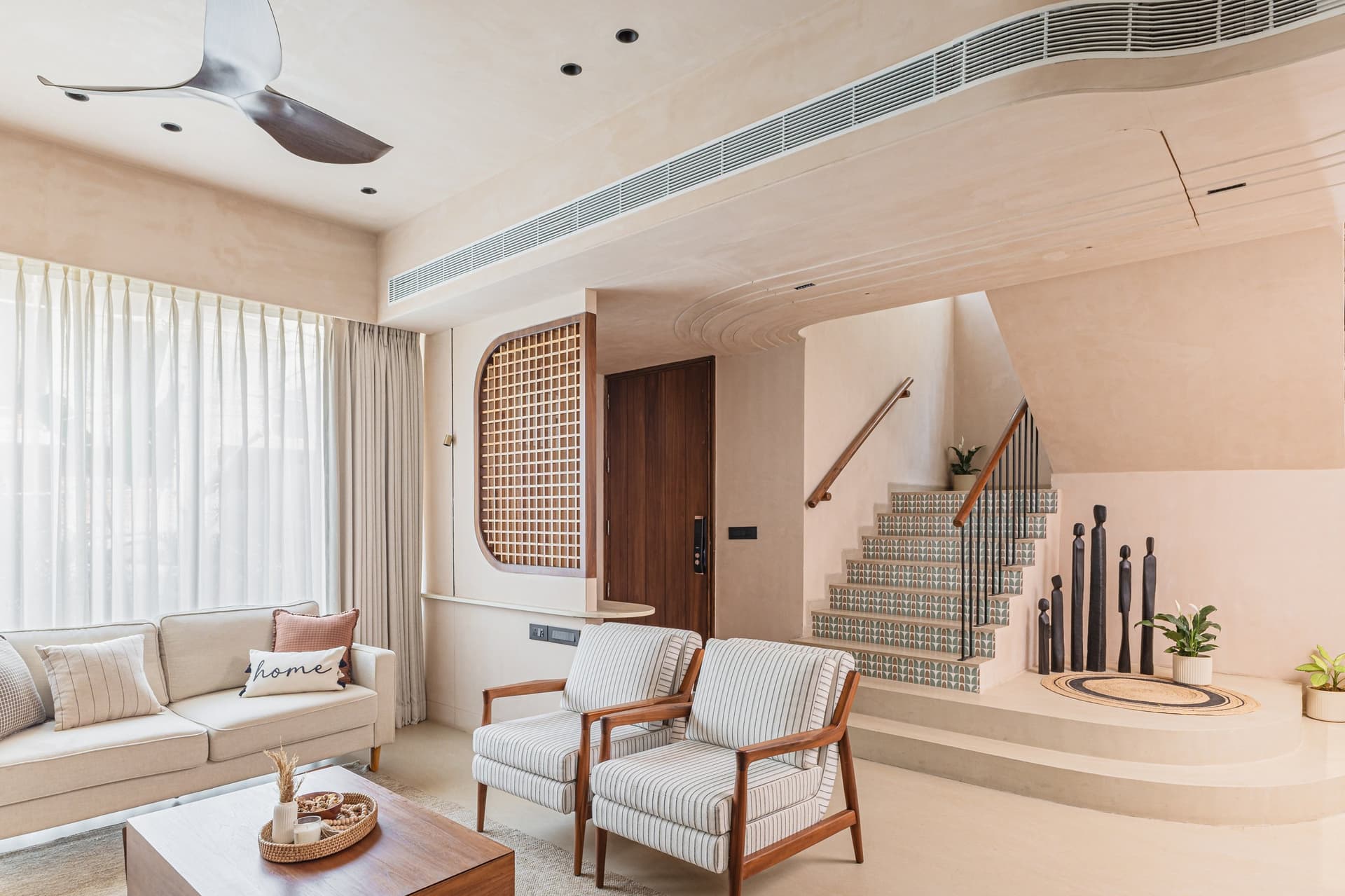 The living room read against the staircase: an arched timber jaali anchors the room to its Vadodara setting