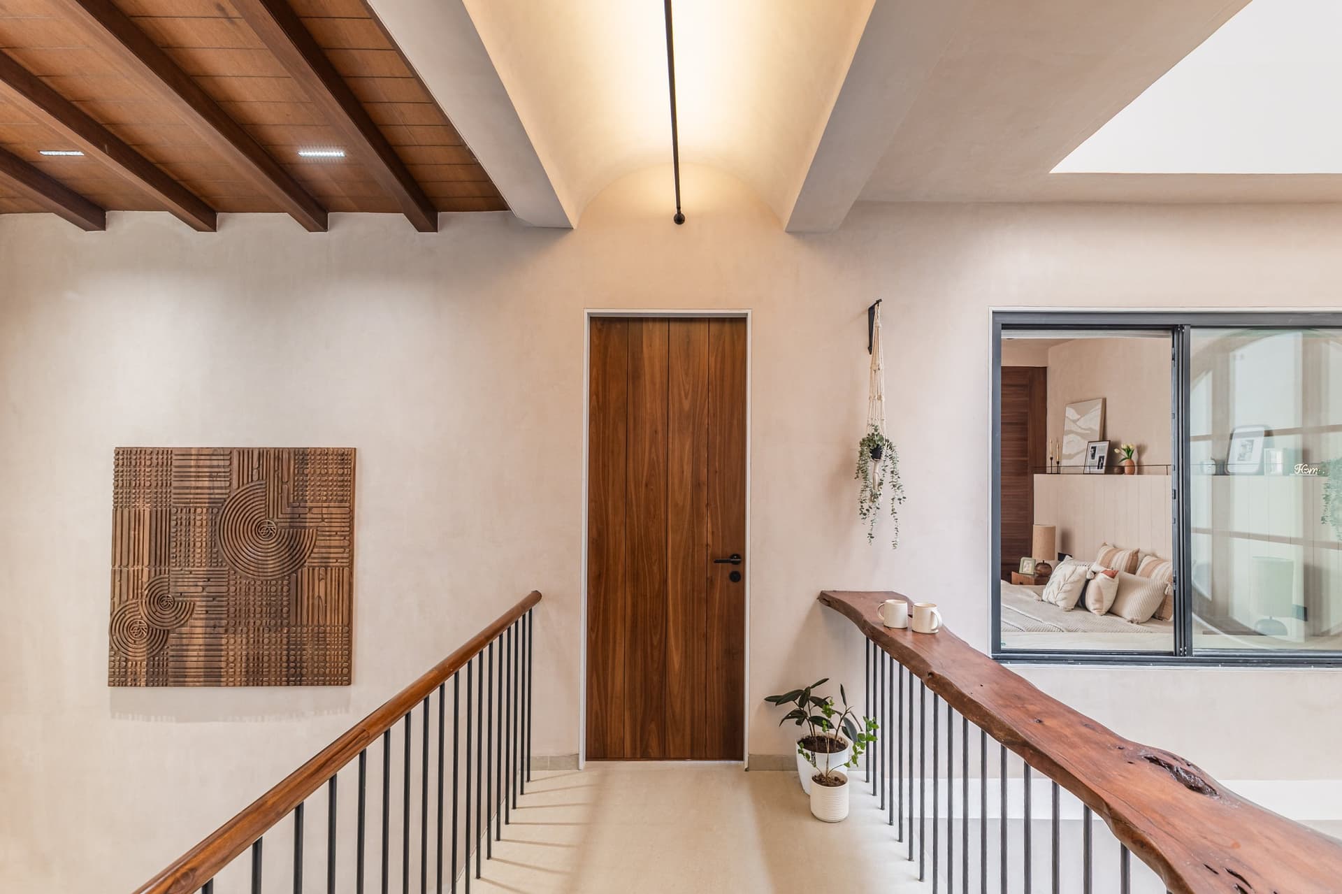 The upper passage: exposed wooden beams, a vaulted ceiling, and a live-edge handrail running the balustrade