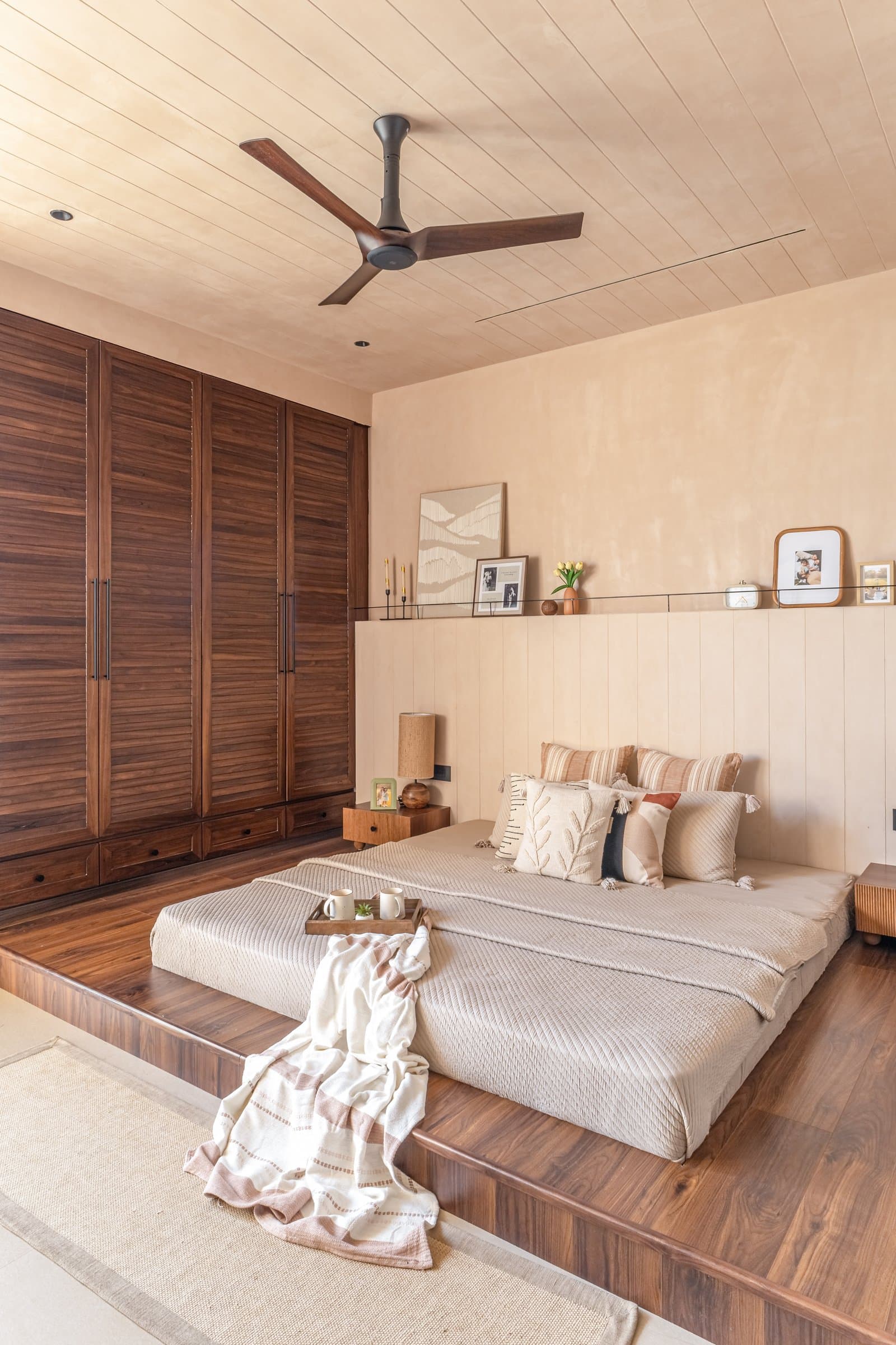 The master bedroom, where a panelled headboard wall and a wood-clad ceiling lower the room's apparent height