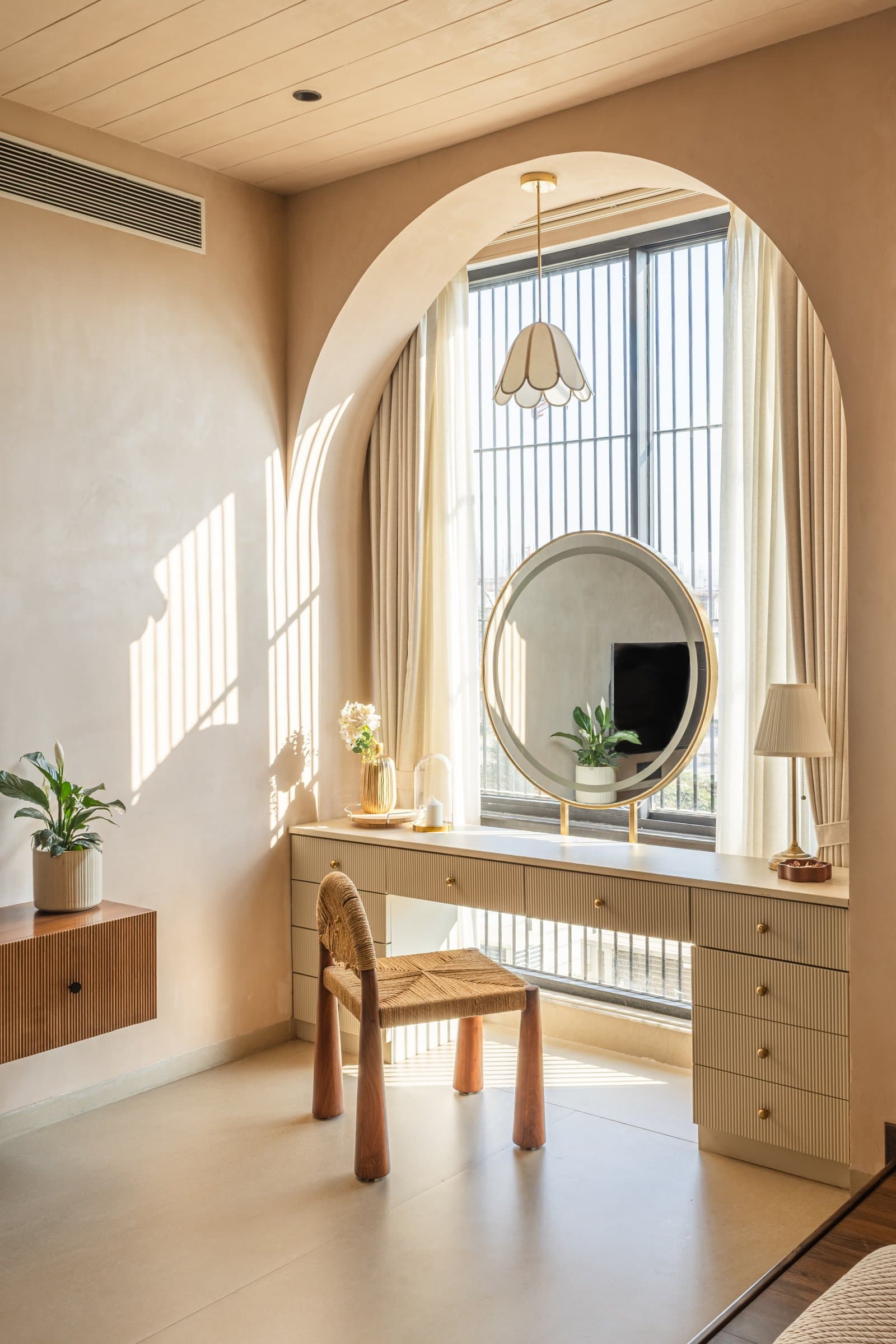 A vanity alcove within the master, set into a tall arched recess with a brass-framed round mirror