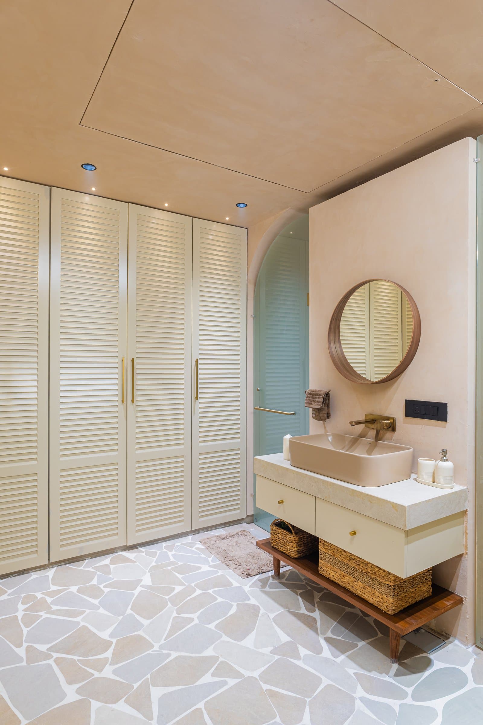 The master bath: louvred cream wardrobes, a rectangular vessel basin, and a tessellated stone floor