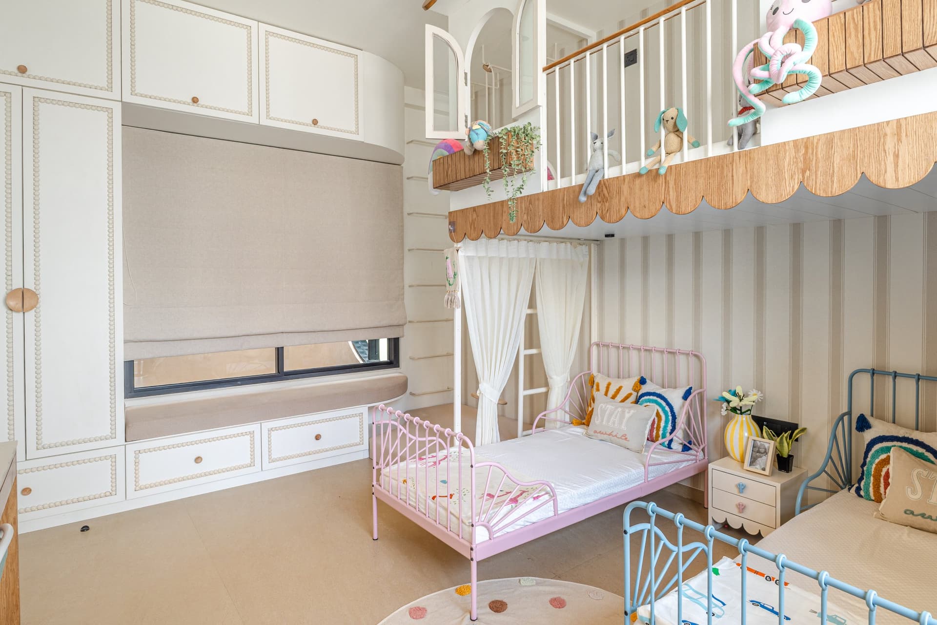 A built-in window seat and panelled wardrobe show how integrated storage carries the children's room