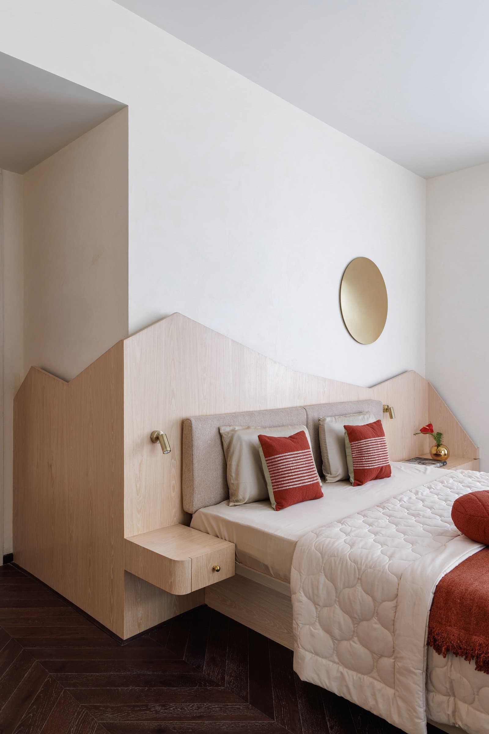 The integrated headboard wraps around the bed and steps down on either side to become side tables, then continues as wardrobe paneling beyond