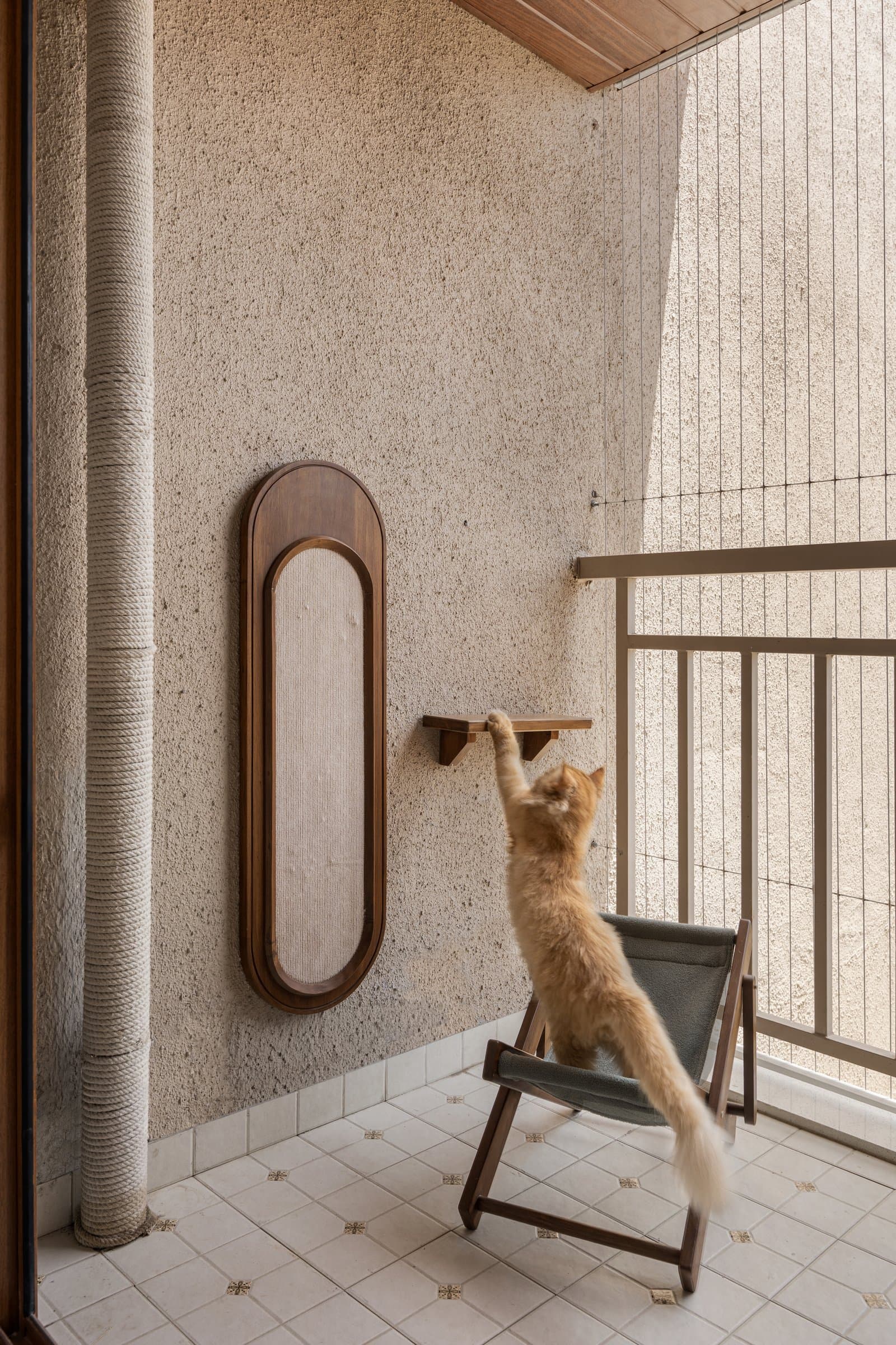 The balcony, reimagined as a cat play area: a rope-wrapped climbing column, a cantilevered timber ledge, and a framed scratch pad within a rounded surround