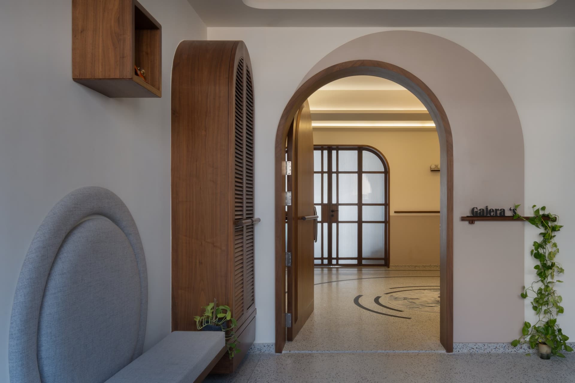 The inner threshold: a fluted-glass-and-walnut door set within a plastered arch