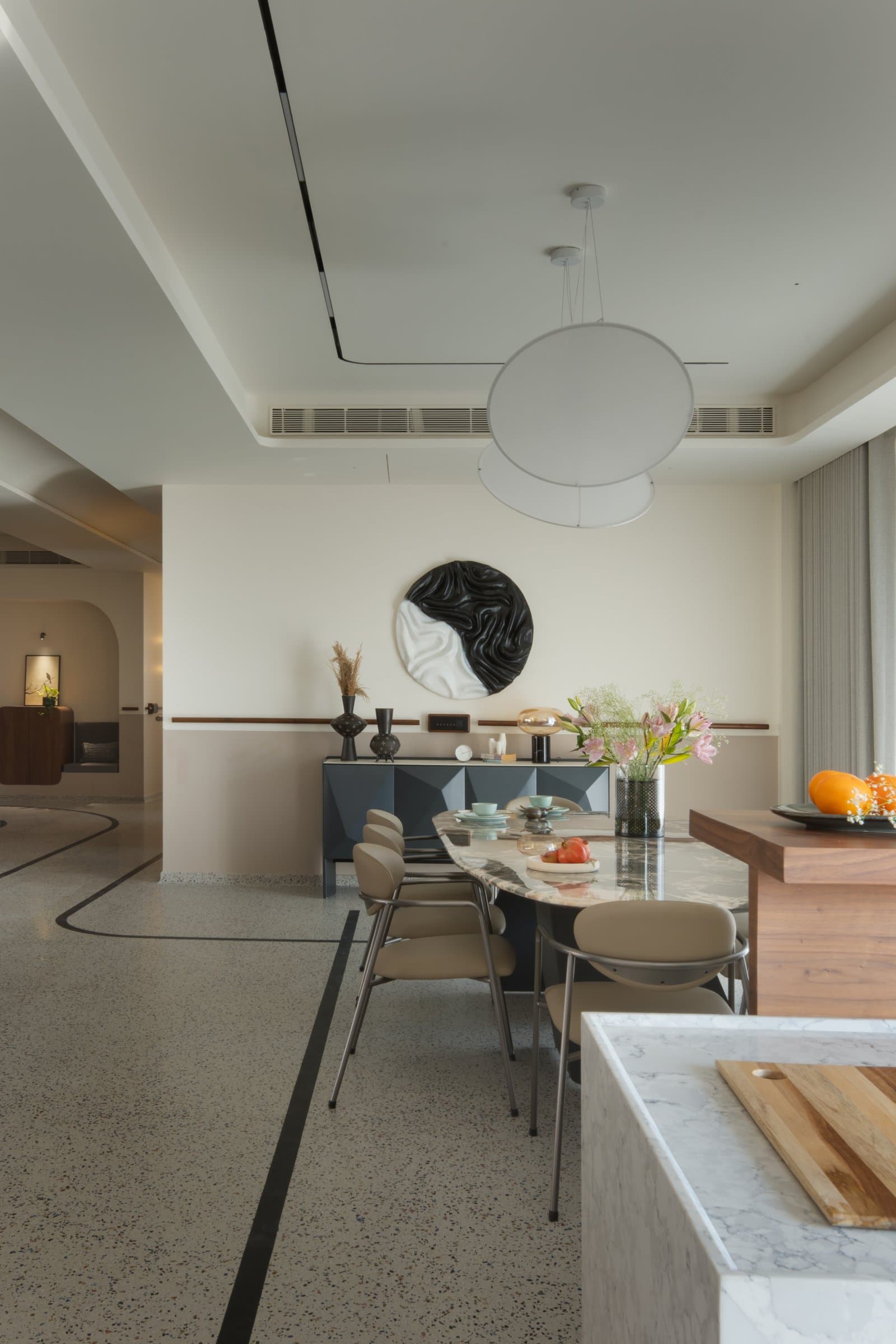 The dining area, anchored by a marble-topped oval table and a faceted sideboard