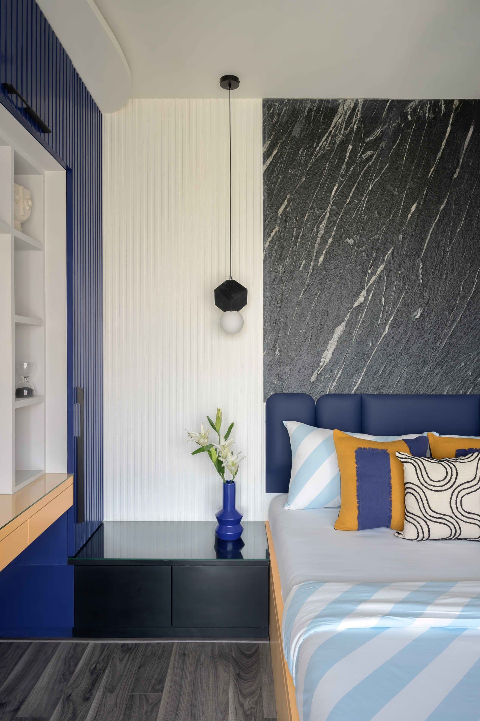 A faceted black pendant against the headboard's stone-and-blue composition