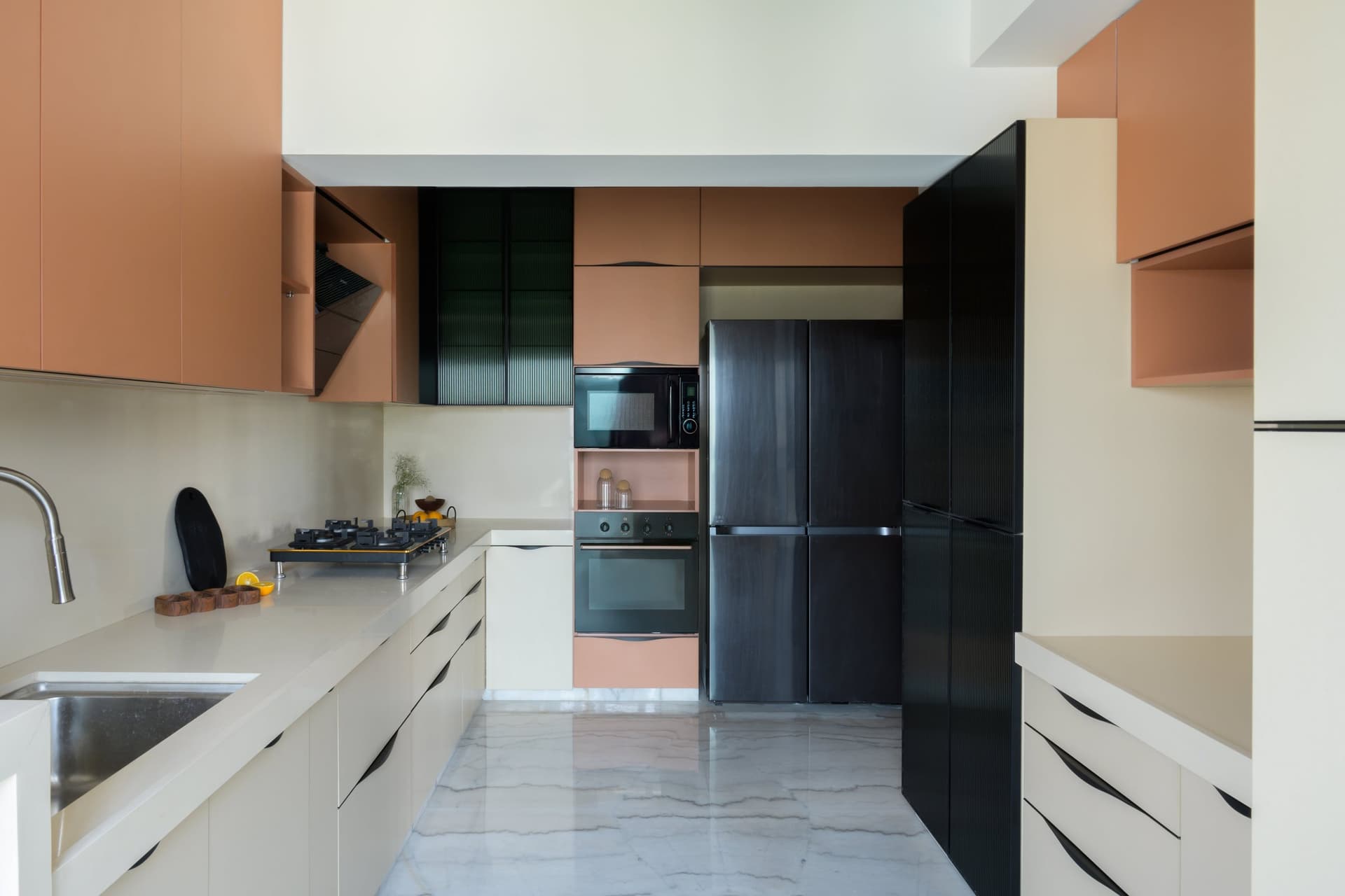 The kitchen commits to peach uppers, cream base cabinetry, and matte black appliances