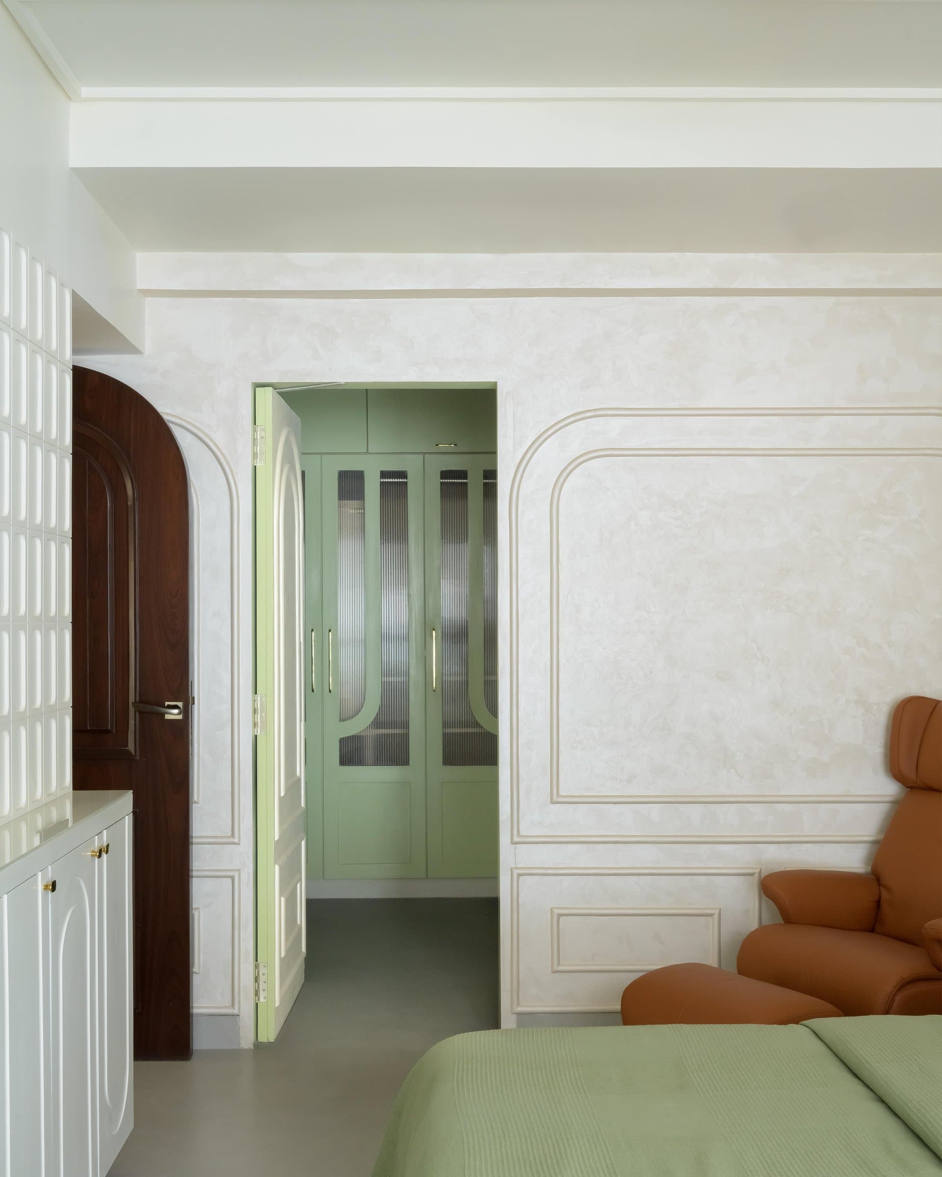 A sage-green dressing area glimpsed through the master bedroom's open doorway