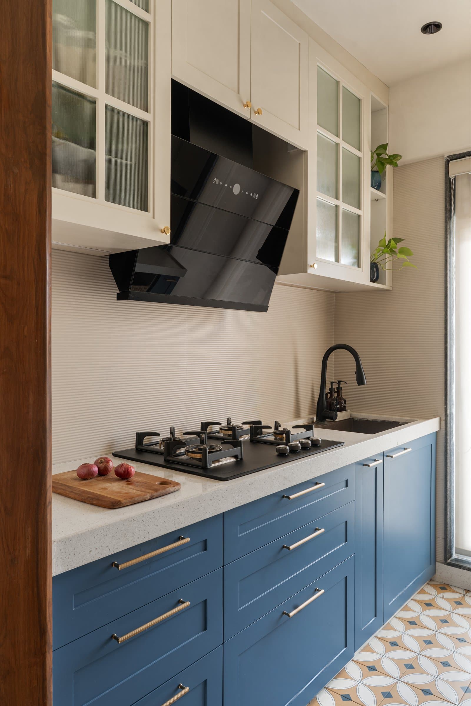 The kitchen, where a cobalt-blue lower run, cream upper cabinets, and a patterned cement-tile floor introduce the home's only saturated colour