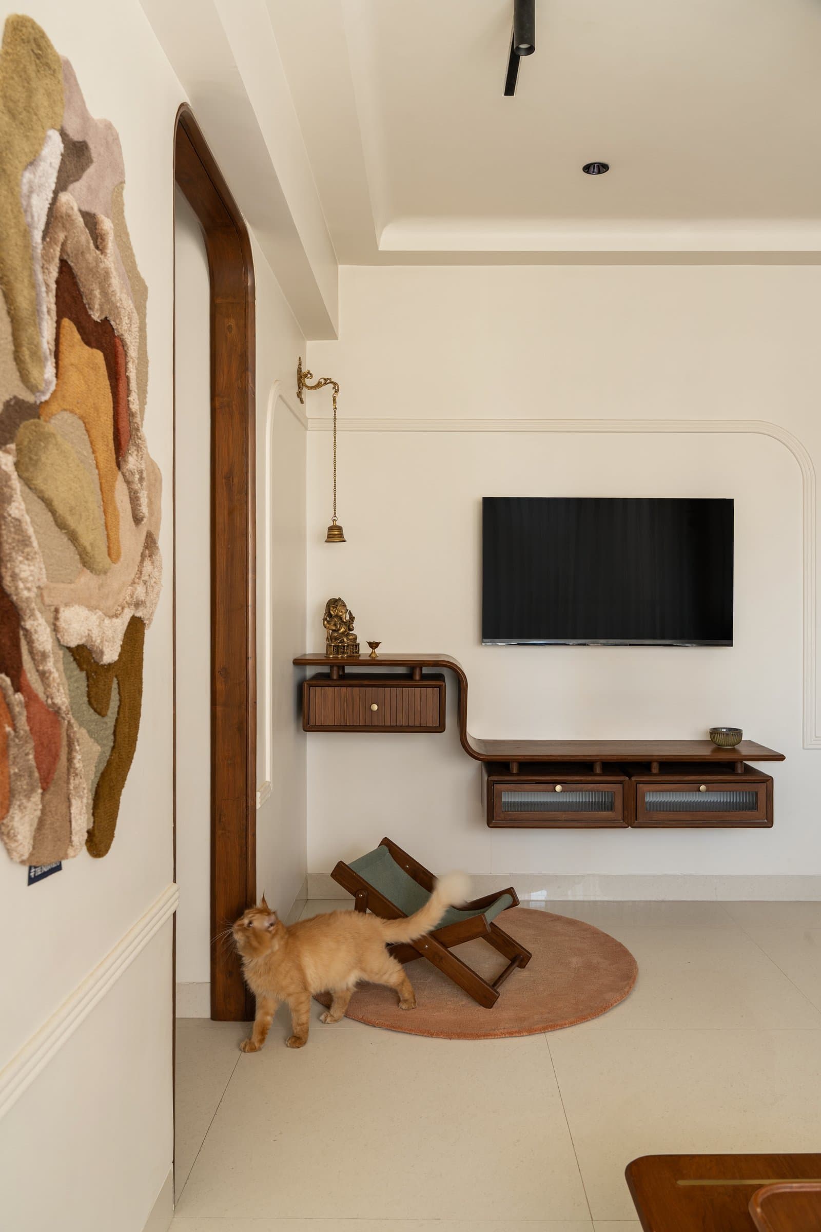 The television unit folds a compact temple into its curved teak joinery, with fluted glass shutters echoing the arched doorway
