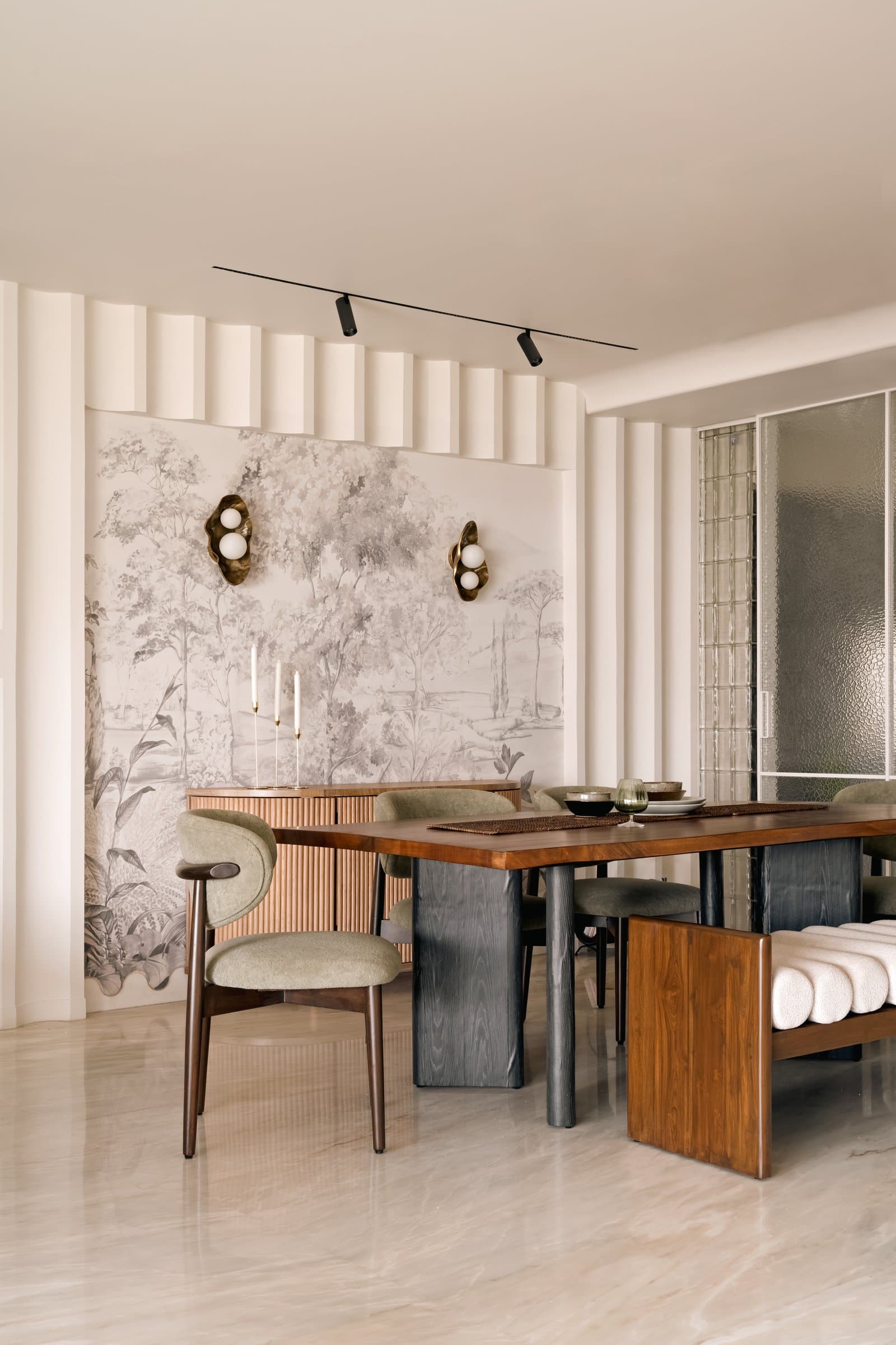 Closer to the table: cane-fronted credenza, organic brass-and-glass sconces, and a wood-and-blackened-base table