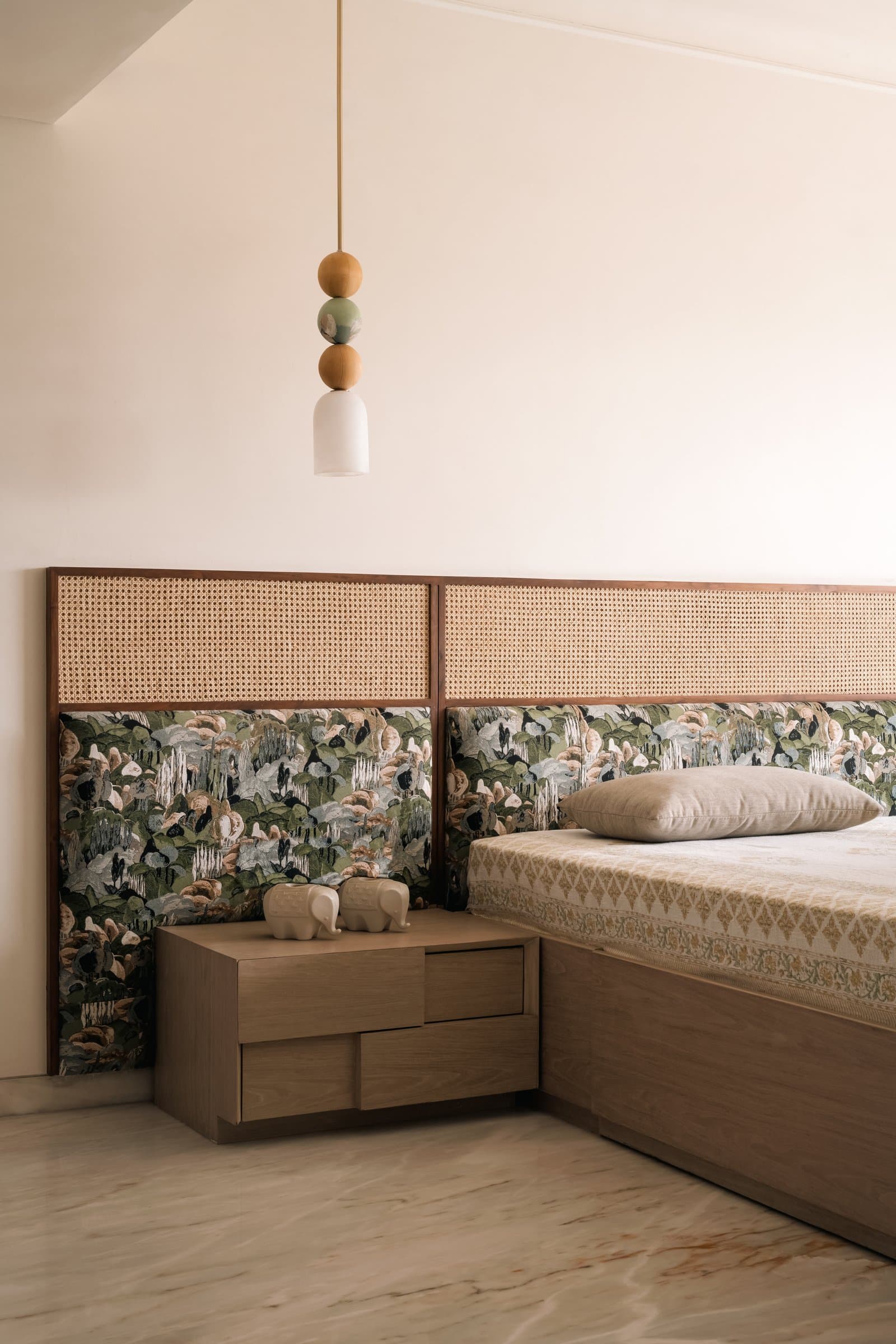 The master bedroom's custom headboard pairs woven cane with a printed botanical panel, the home's only patterned indulgence