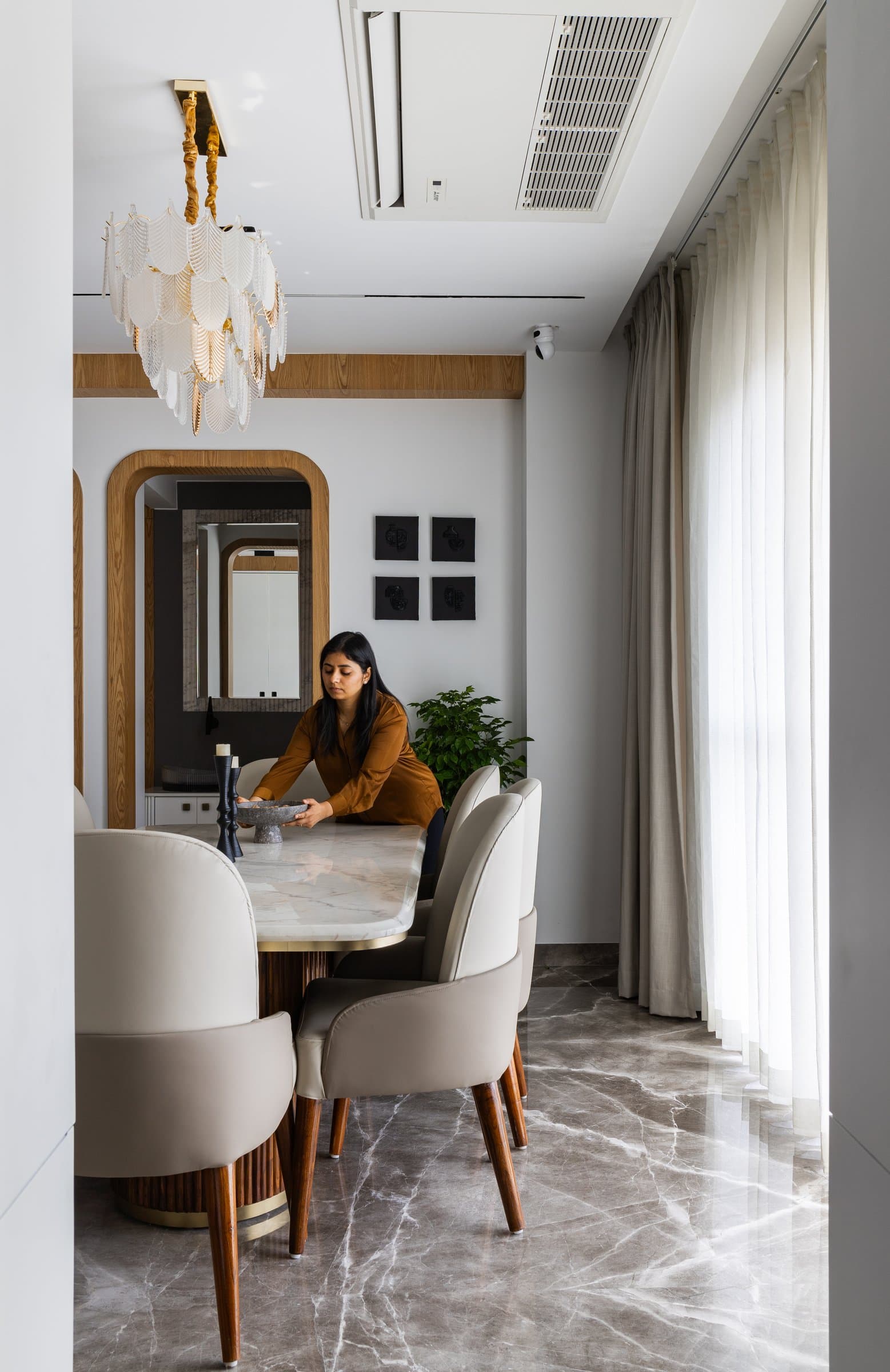 The dining seen lengthwise, where an arched mirror in a wooden frame doubles the room's depth