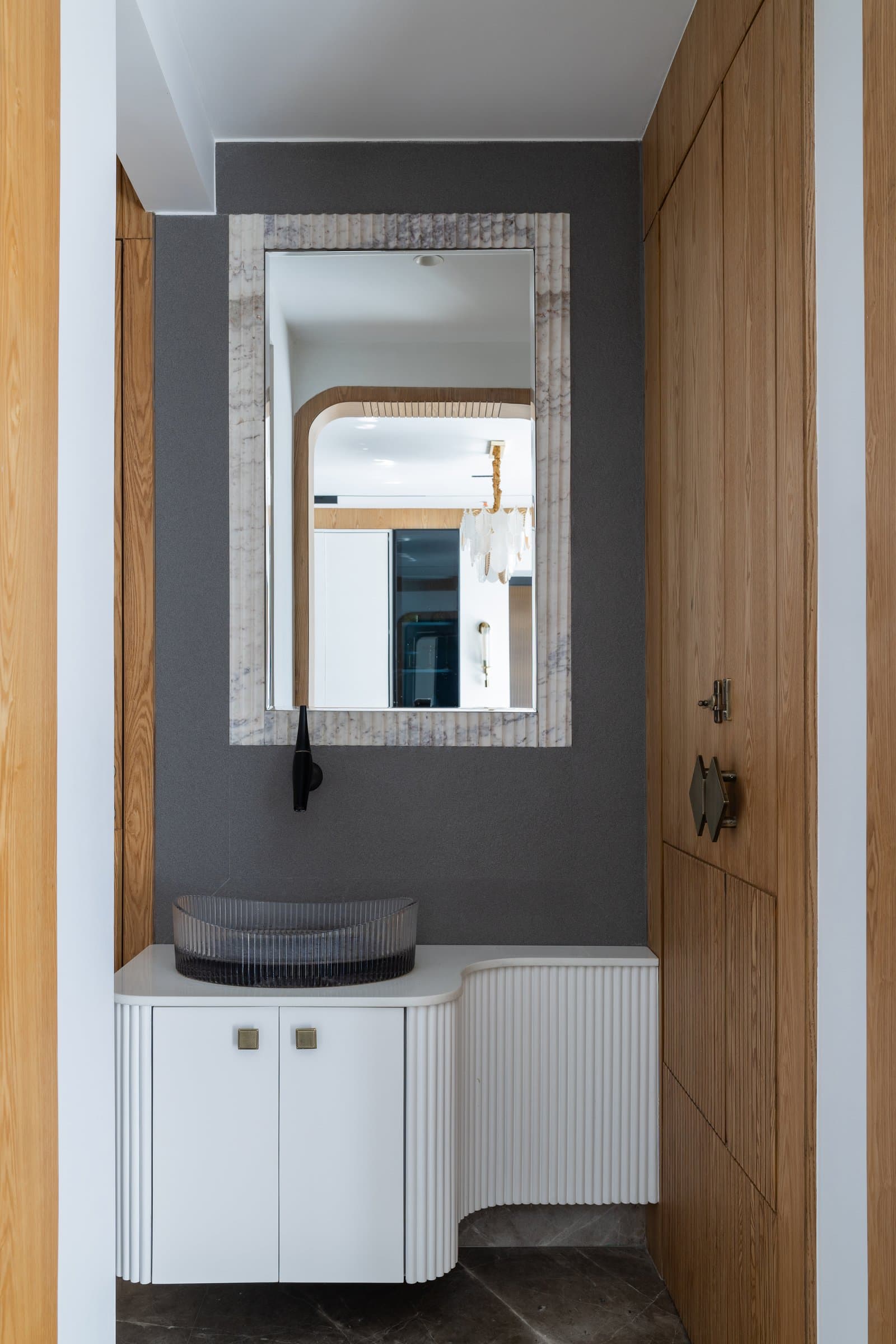 The powder area, where fluting is distilled into a sculpted curved vanity against a charcoal wall