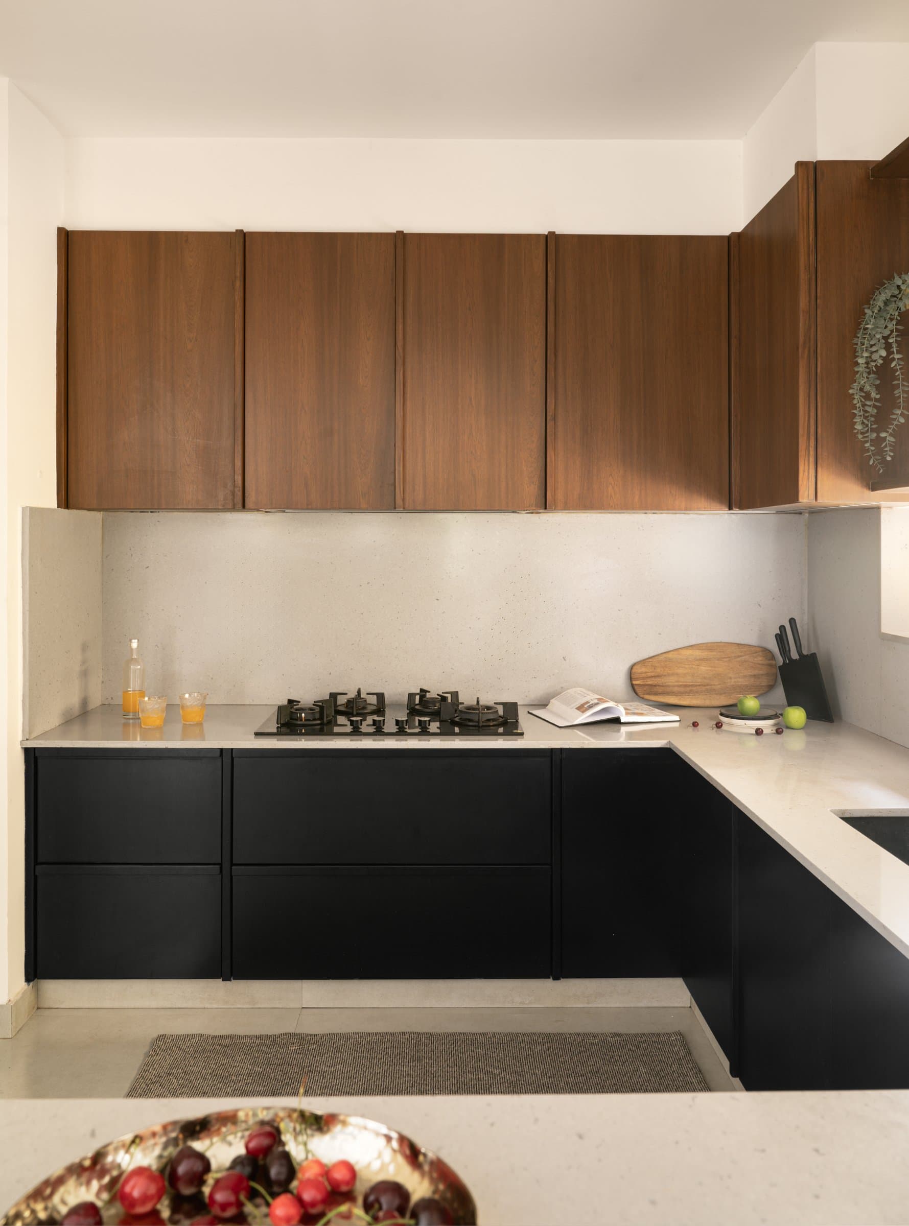 The petite kitchen, where matte black base units sit beneath a pale quartz counter and warm oak uppers run in continuous grain
