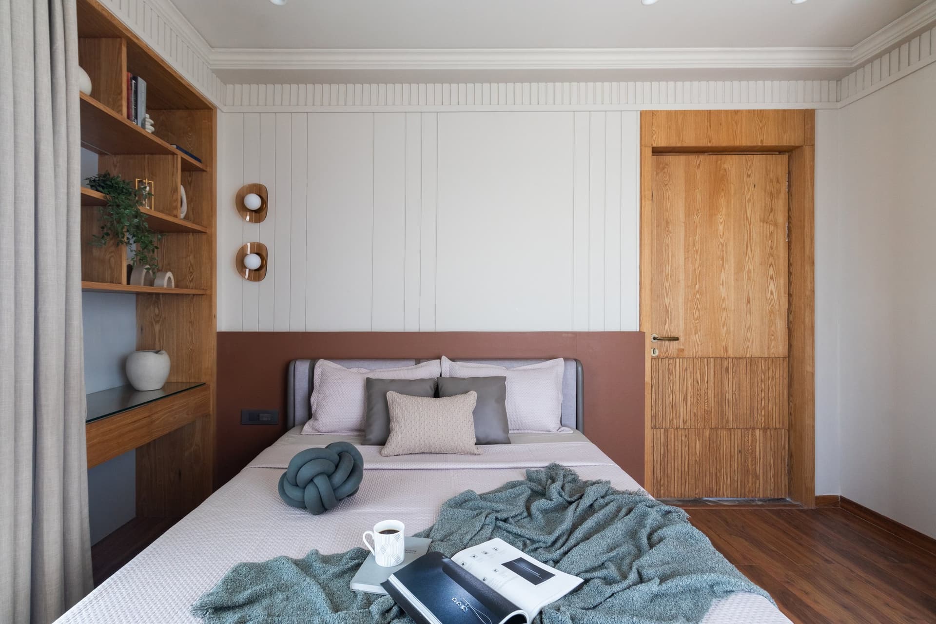 The first guest bedroom, where a terracotta-toned band behind the bed grounds an otherwise pale envelope