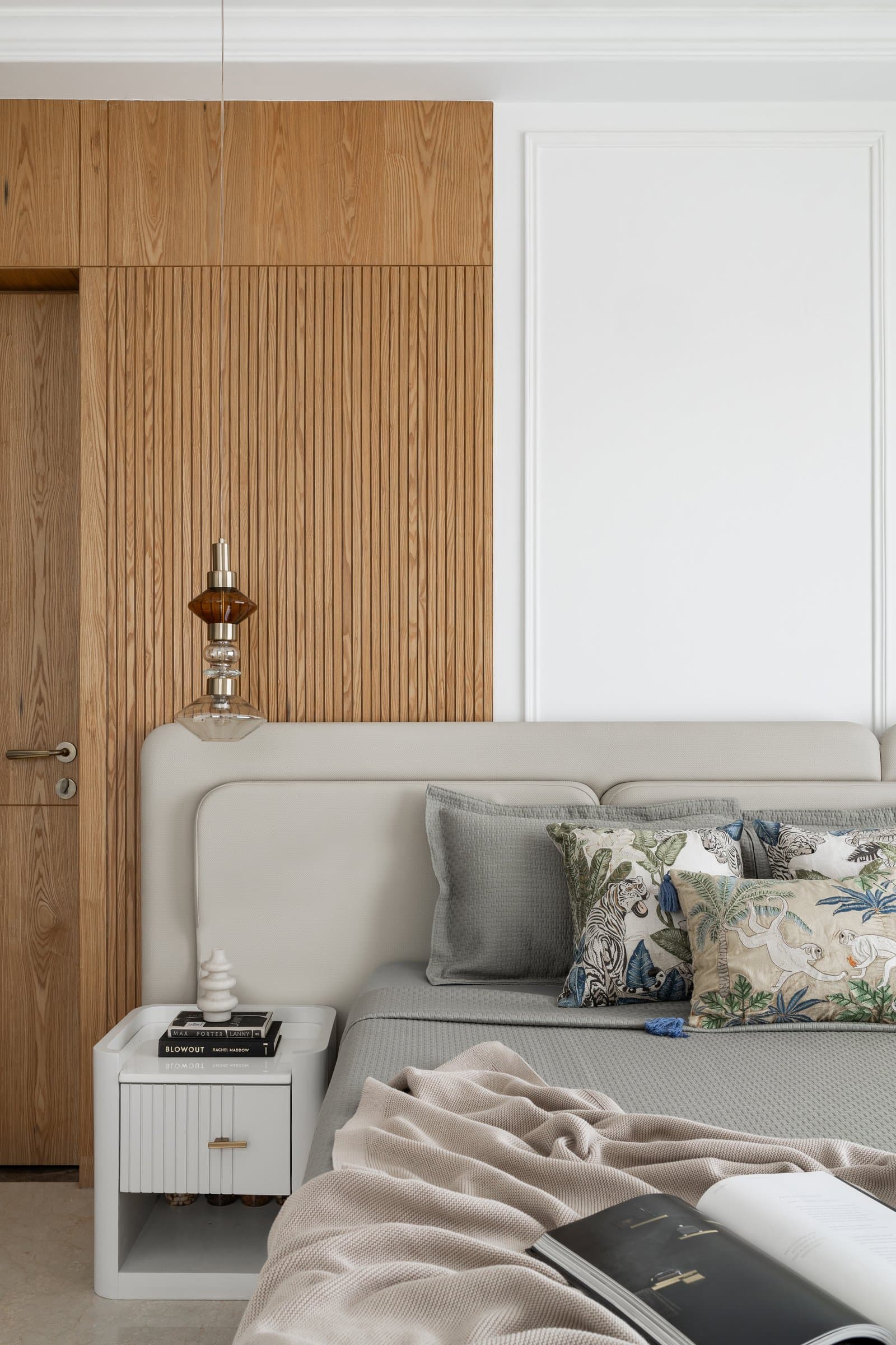 The master bedroom headboard wall, articulated through tall vertical reeding in warm wood