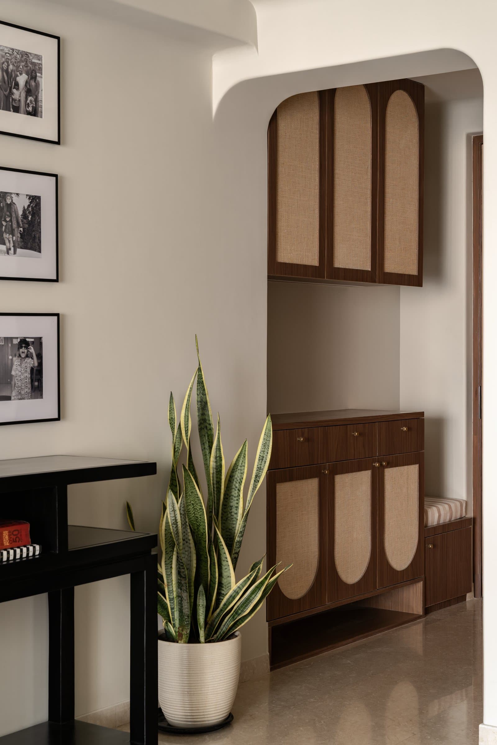 The entry niche: cane-fronted walnut joinery framed within a softly arched plaster reveal sets the home's grammar of craft and restraint