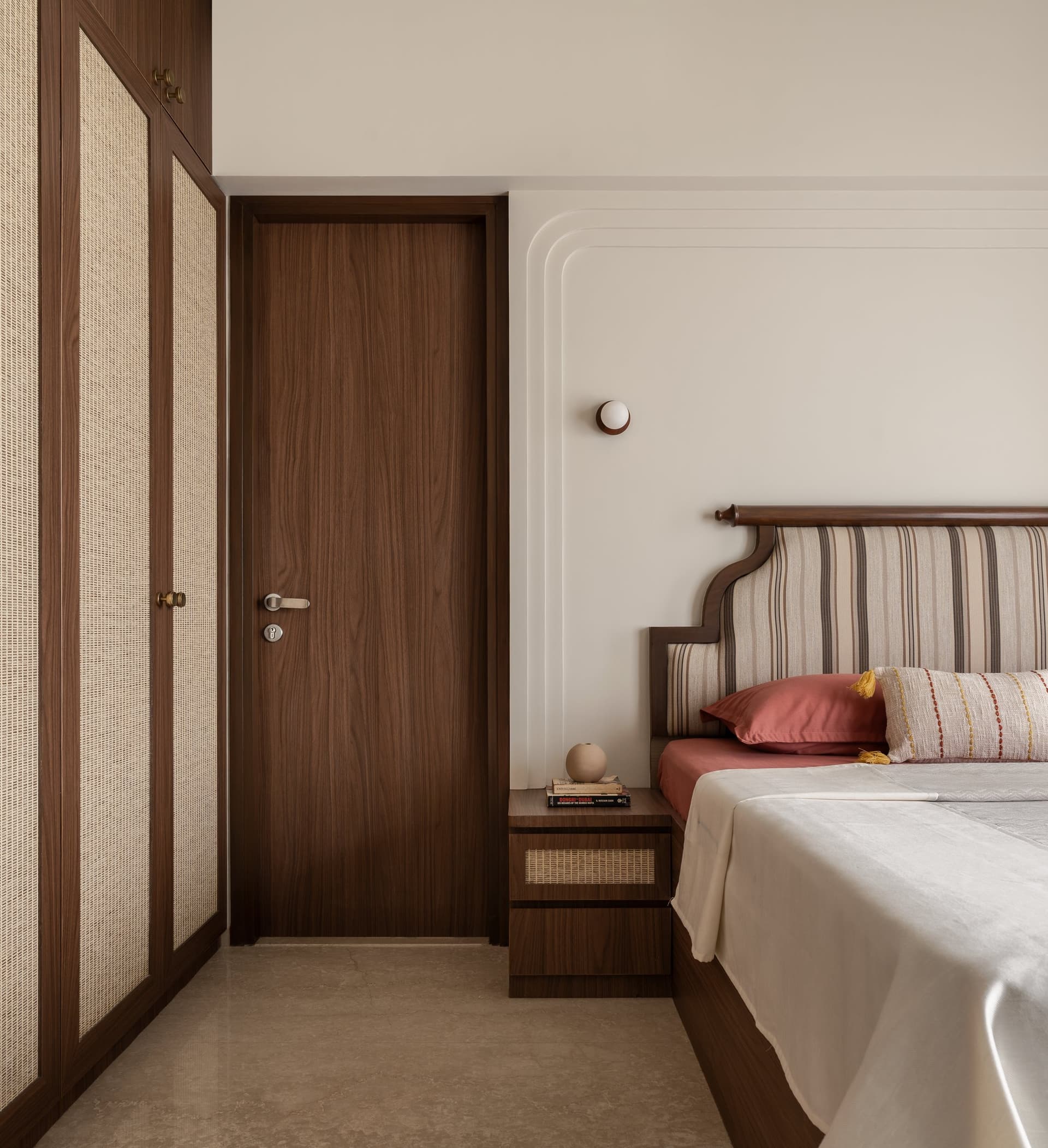 A wider view of the master bedroom resolves its tonal logic of walnut, cane, plaster, and terracotta