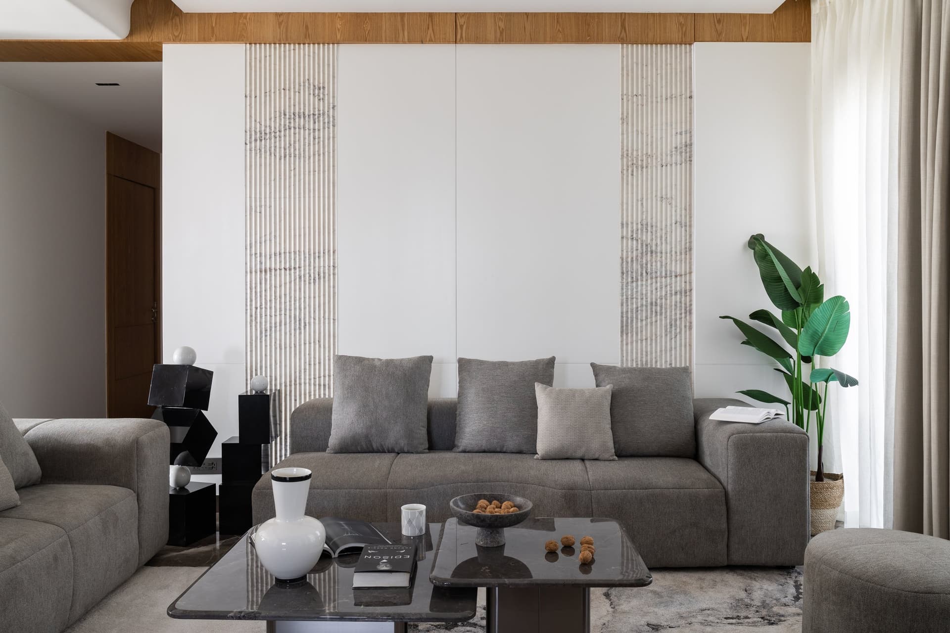 The sofa backwall, where two narrow bands of veined fluted stone frame the seating without competing with it