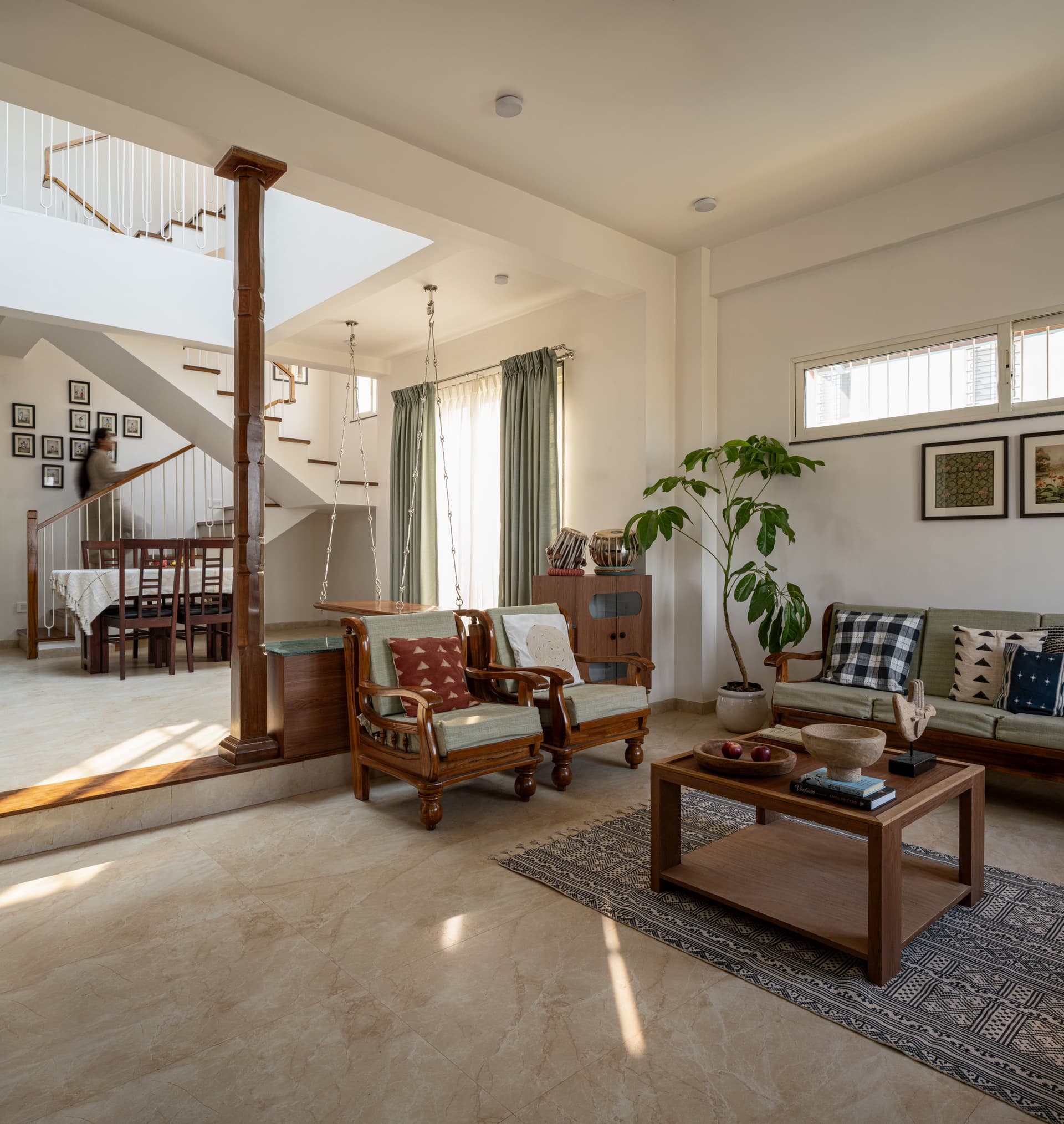 The living room, anchored by the turned wooden column that carries the double-height volume above