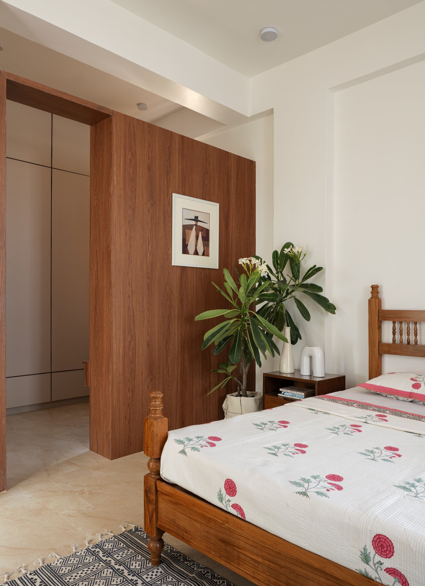 The first bedroom: a teak four-poster against a walnut-veneer wall that conceals the dressing area beyond