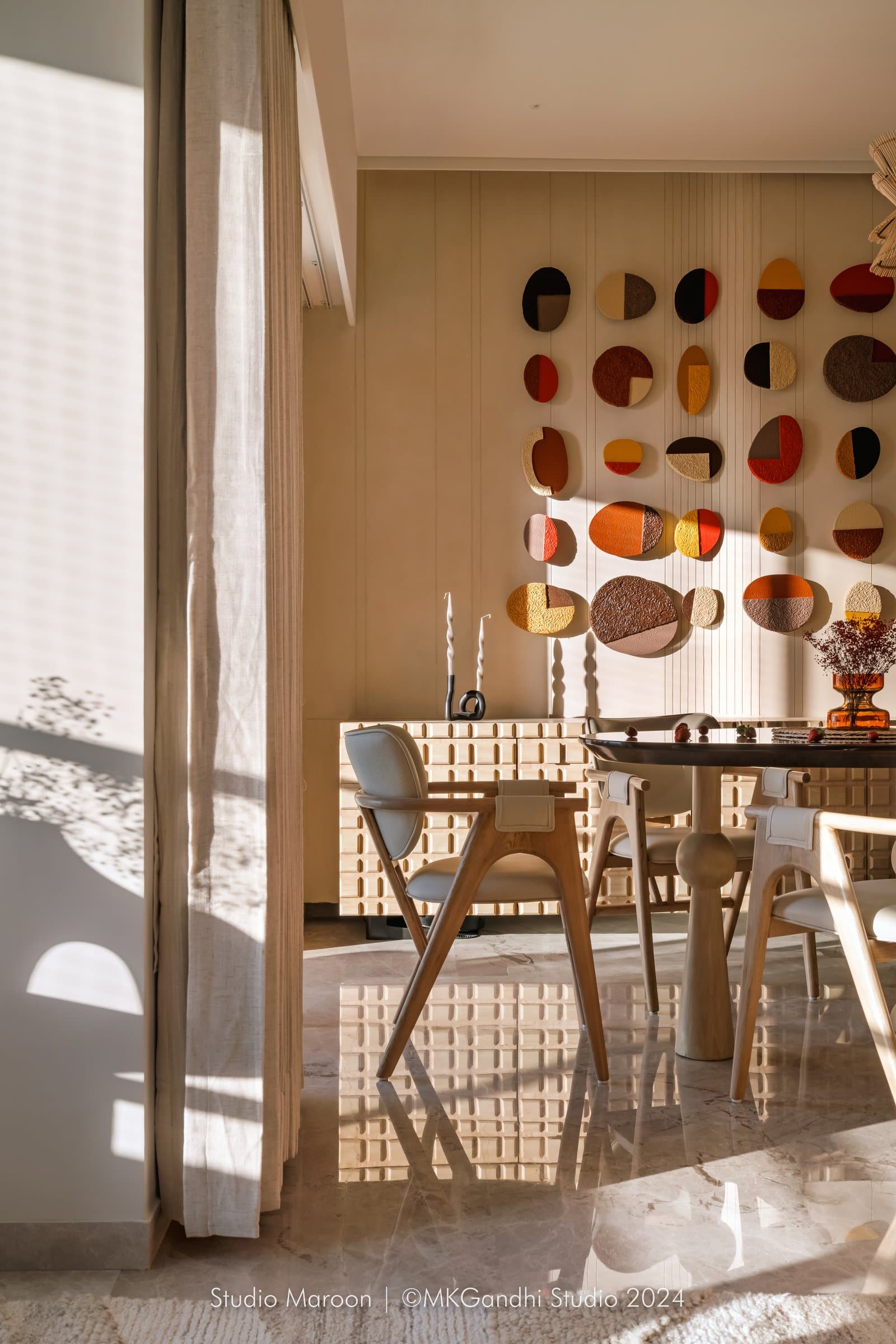 Afternoon light washes over the dining zone, catching the polished stone floor and pale wood chairs