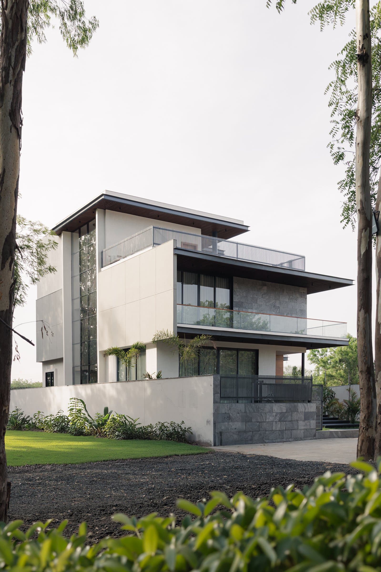 The garden elevation, cantilevered roof planes floating over a stone-clad plinth and a tall glazed corner volume