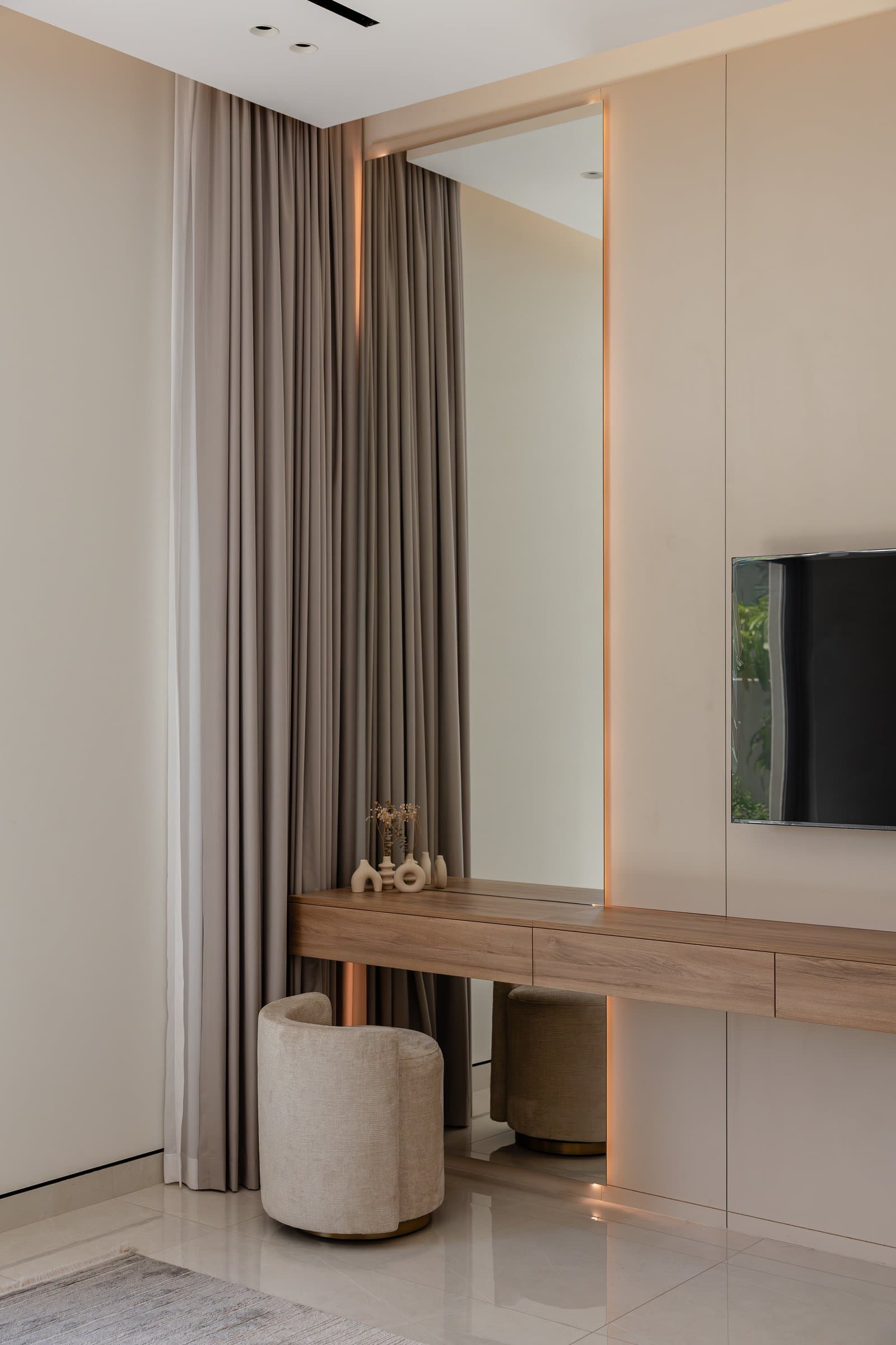 A dressing alcove within the master suite, where a wood-toned floating console and tall mirror extend the room's restraint