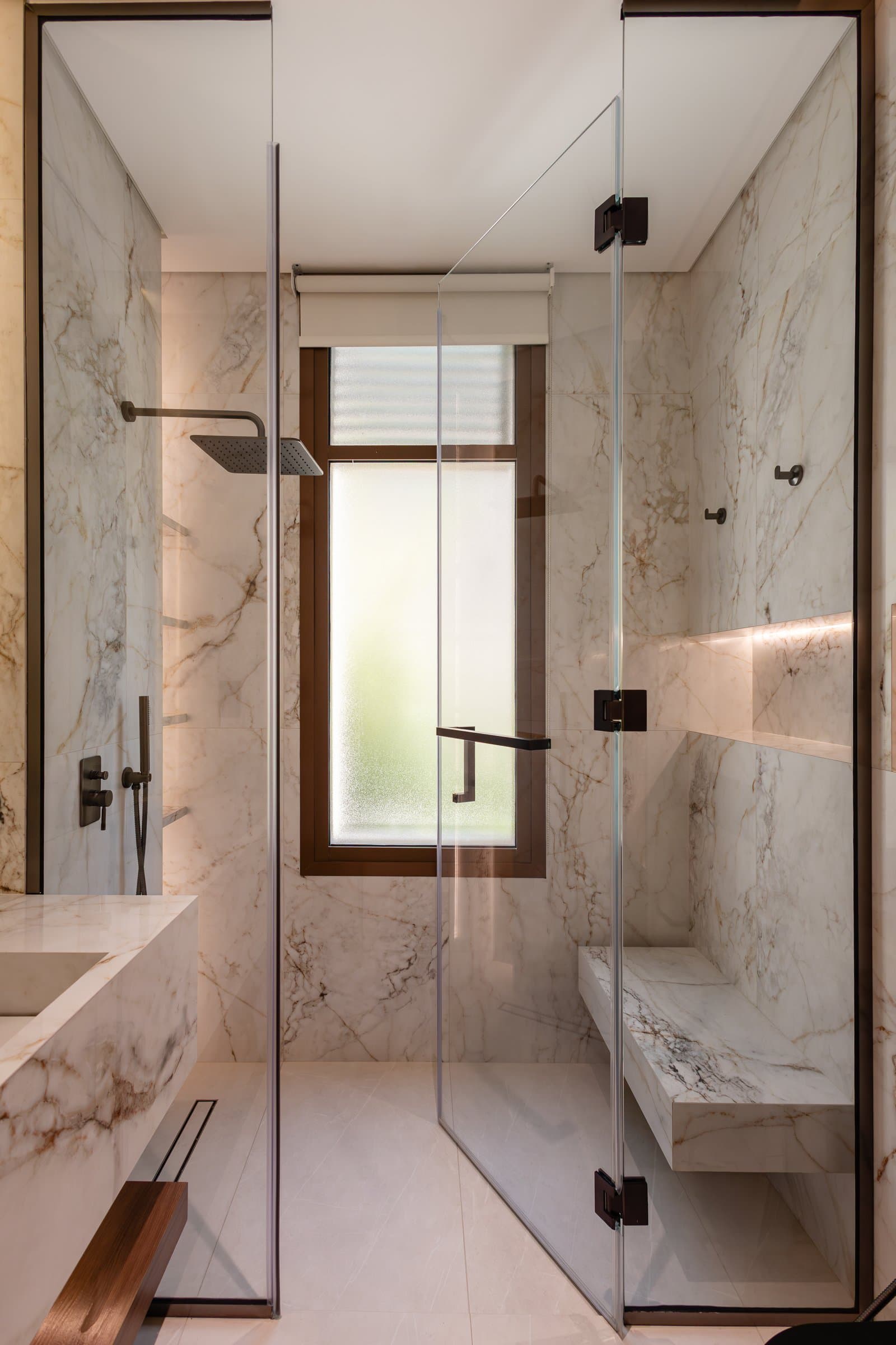 The principal bathroom, wrapped in dramatically veined stone with a carved basin and recessed lit niche