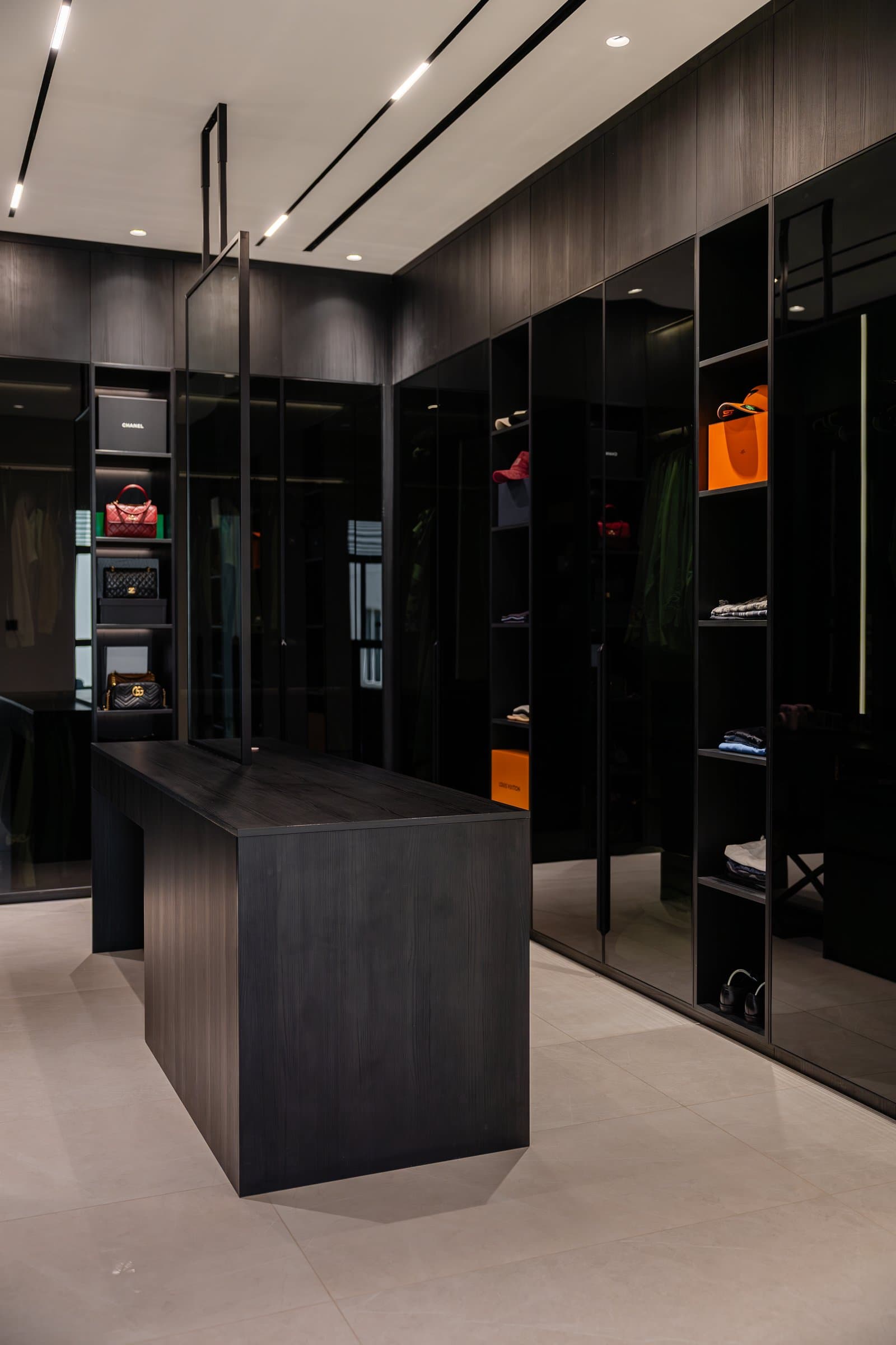 The walk-in wardrobe, where full-height glazed cabinetry and a central island treat dressing as a private gallery