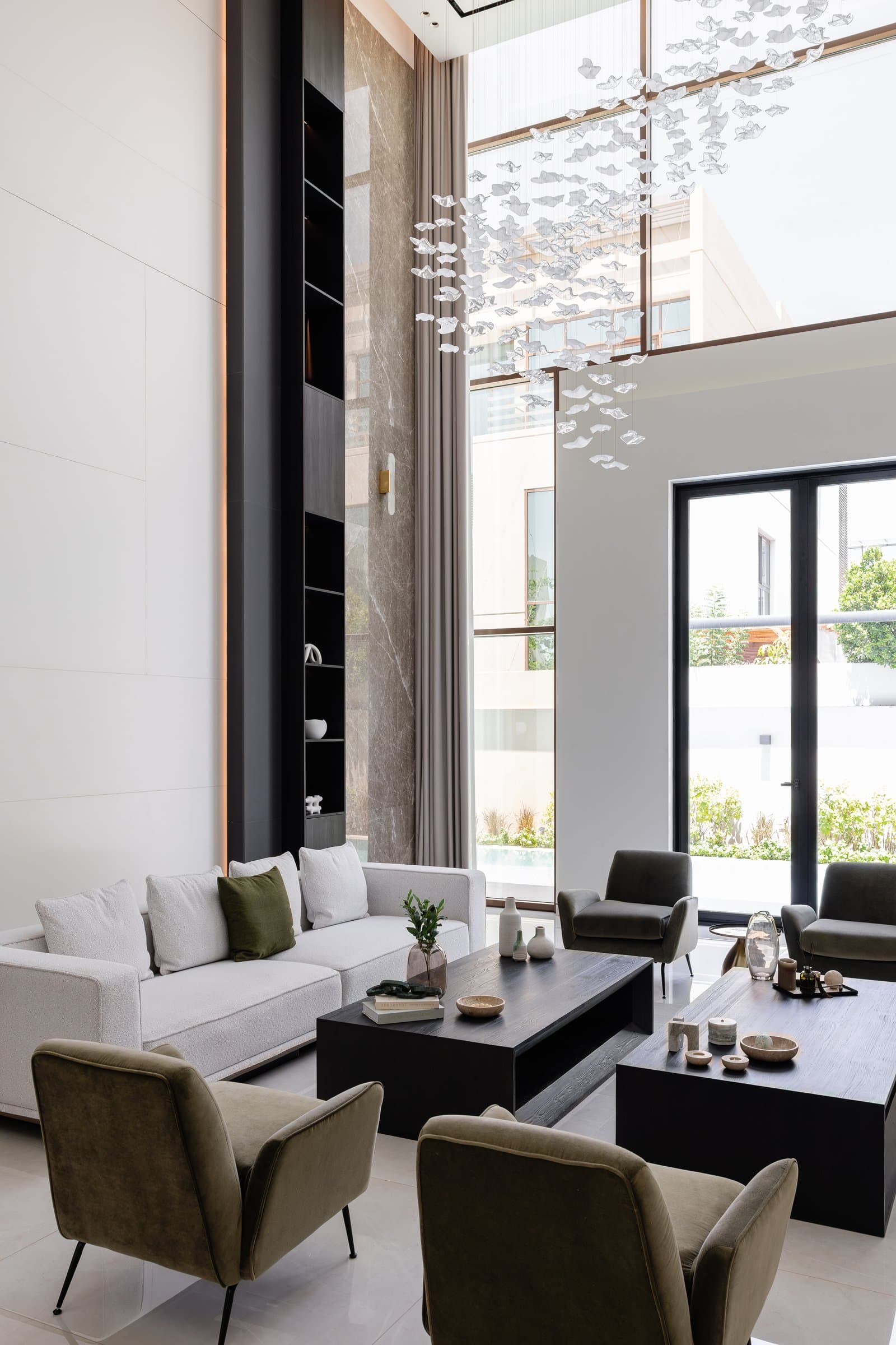 The double-height living room, where a suspended installation of translucent glass forms measures the full vertical scale