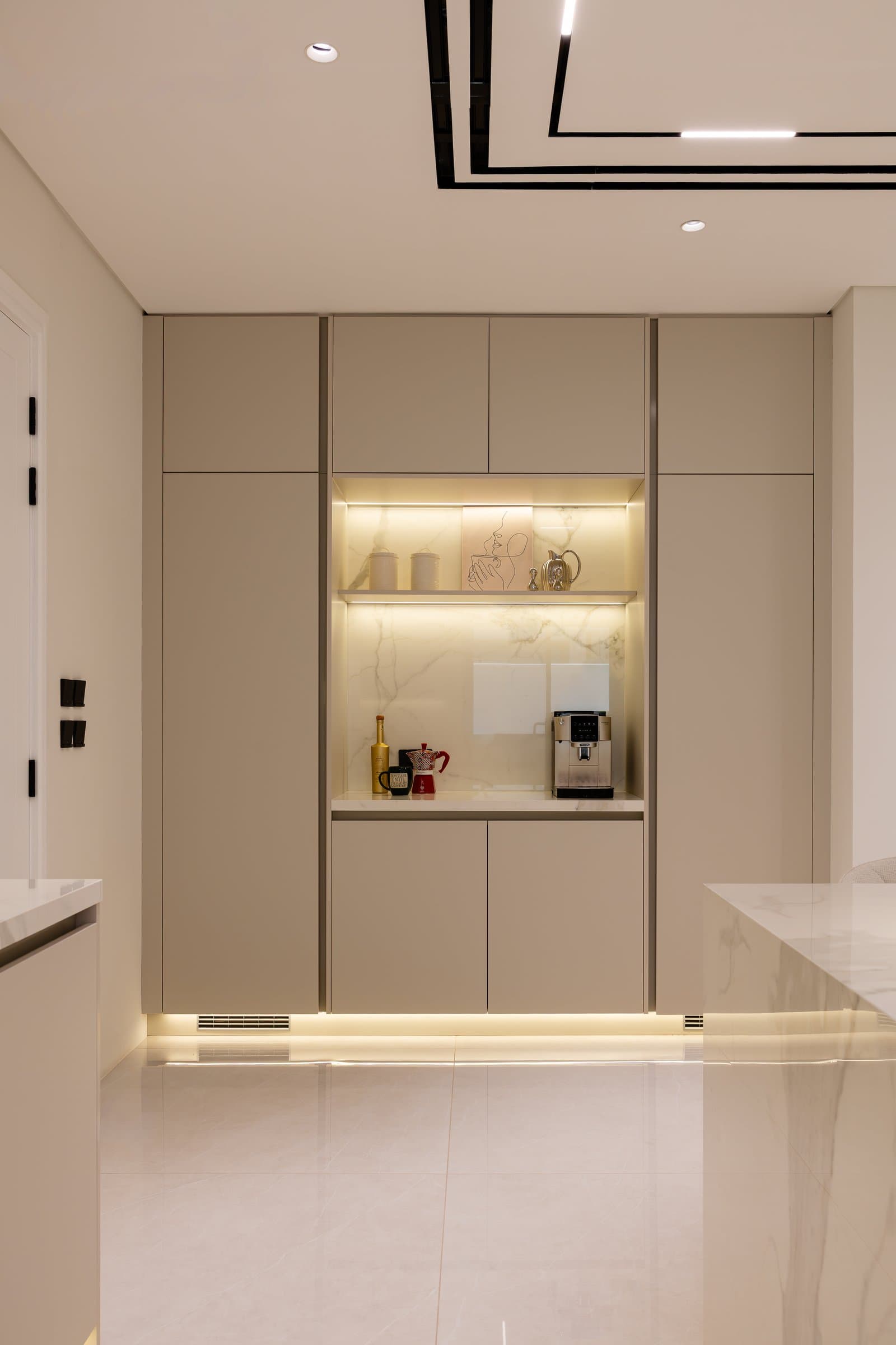 A coffee niche set into the kitchen joinery, where a backlit veined panel turns utility into architecture