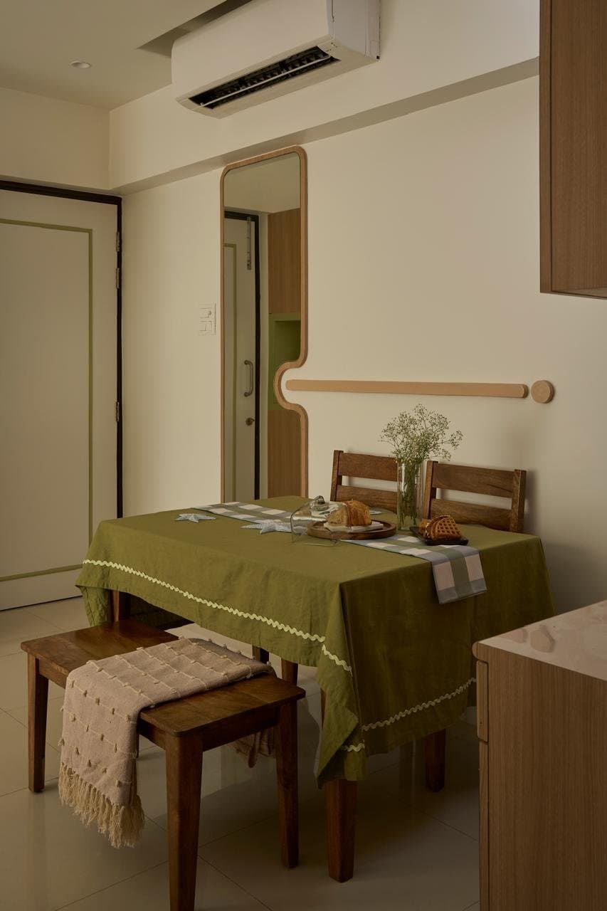 The dining area, where a full-length mirror expands the passage and a warm-toned table anchors the family's daily rituals