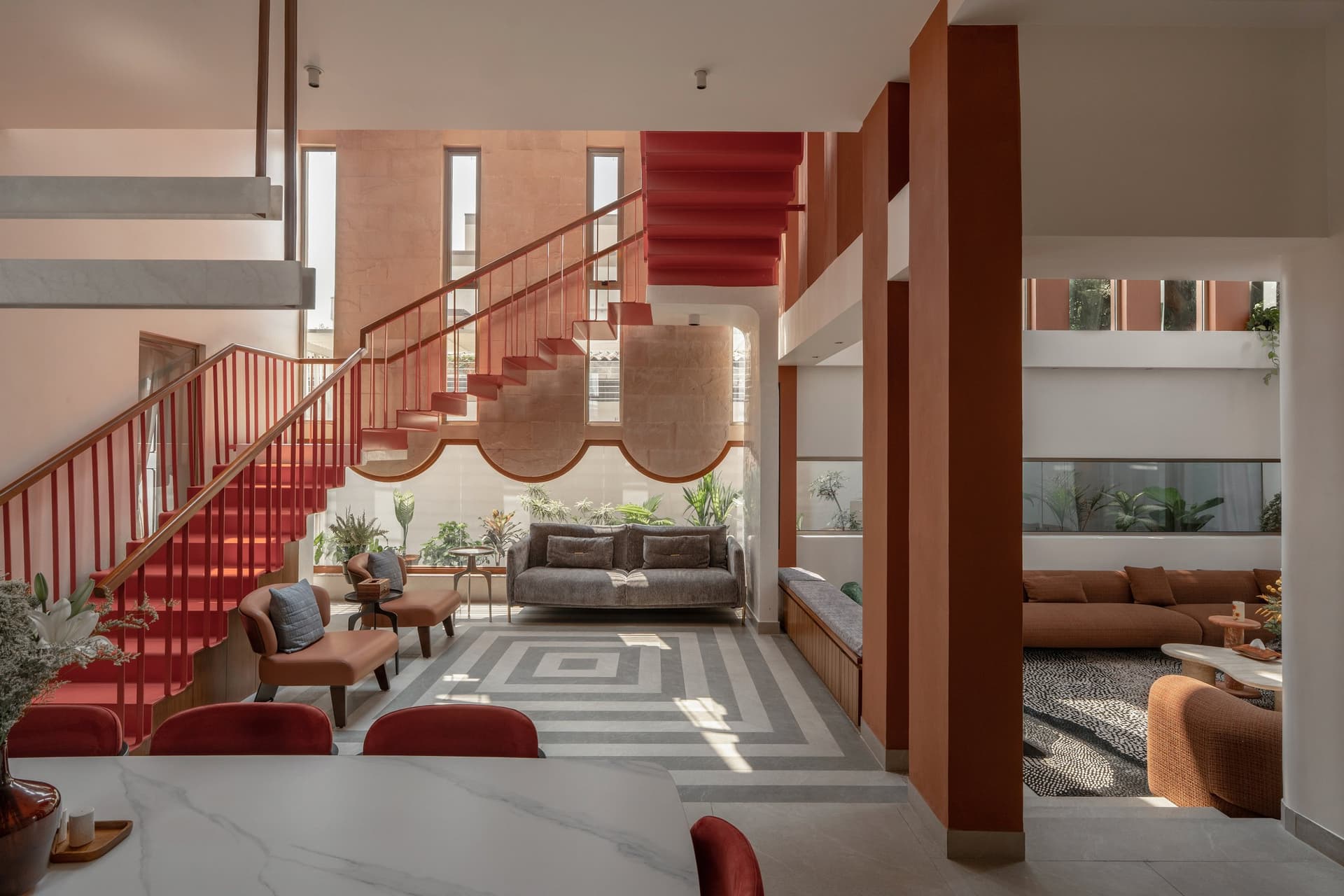 The central living volume, where a terracotta staircase and a scalloped stone arch anchor the home's spatial argument