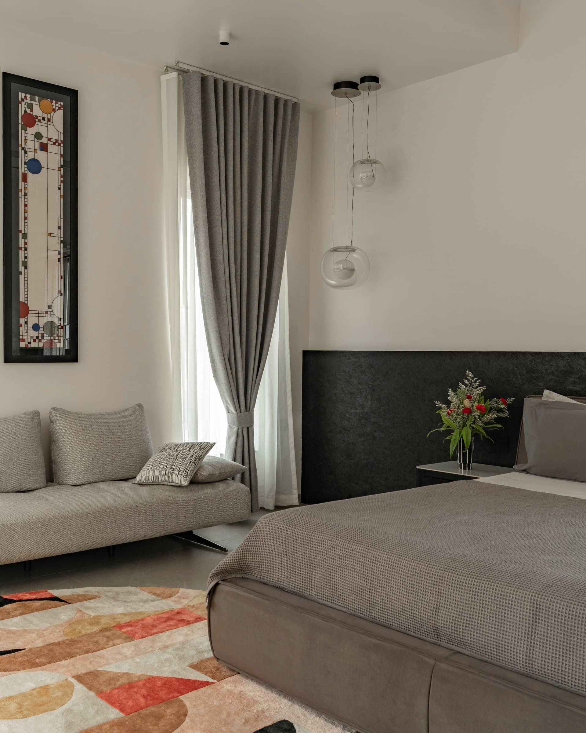 A second bedroom, where a dark textured headboard and paired glass globe pendants set a quieter tone
