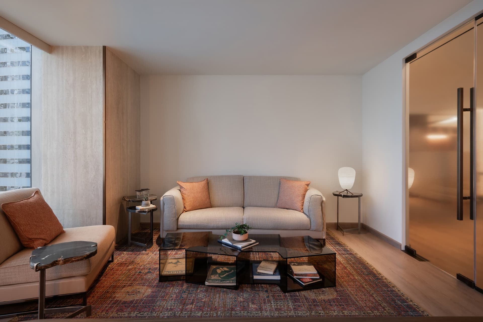 The waiting lounge, where a travertine window recess and a patterned rug soften a room otherwise held in pale neutrals