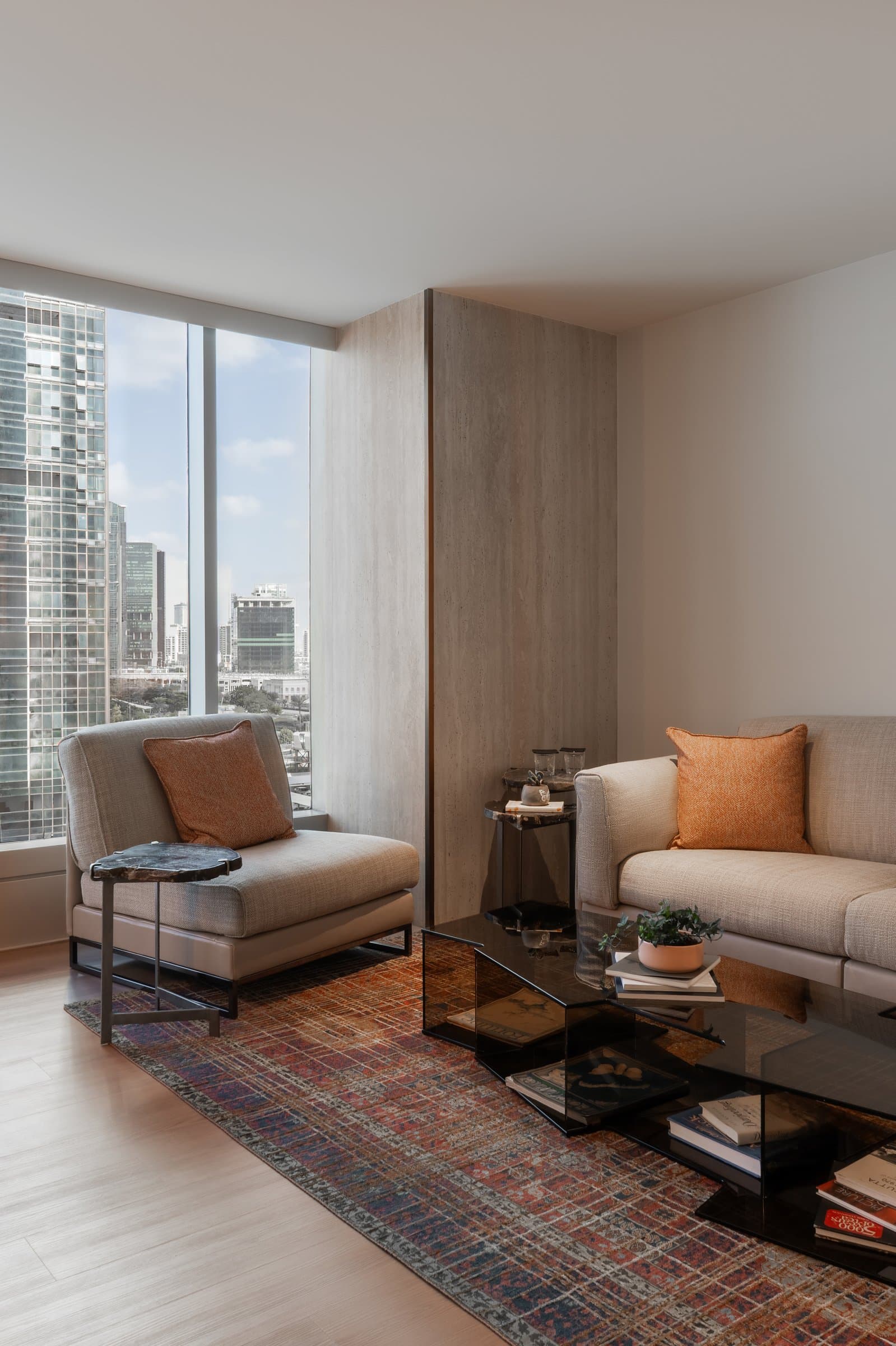 The lounge seen from its window side, opening toward the Dubai skyline through a full-height glazed panel
