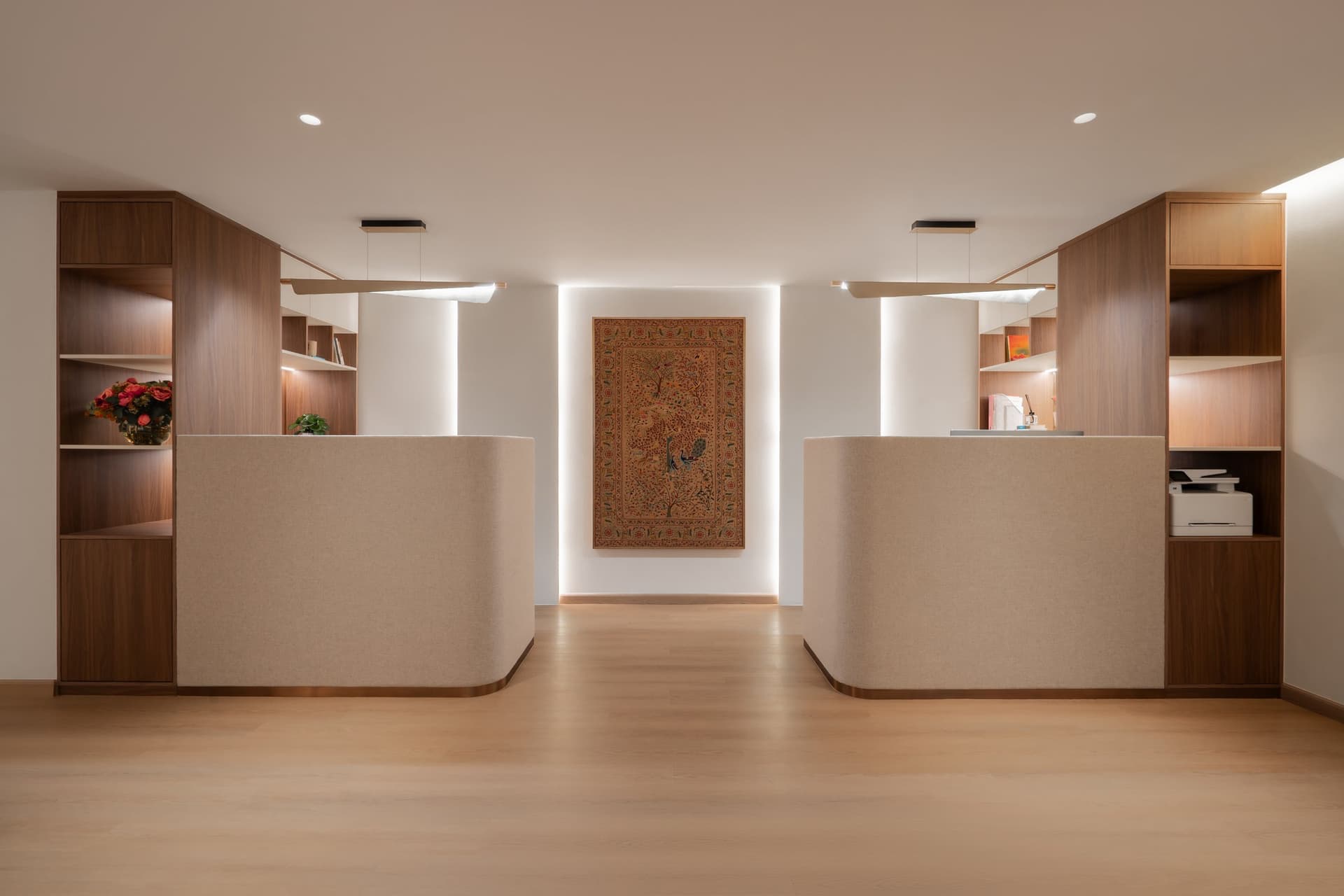The reception, where two fabric-wrapped desks flank a backlit tree-of-life textile at the arrival threshold