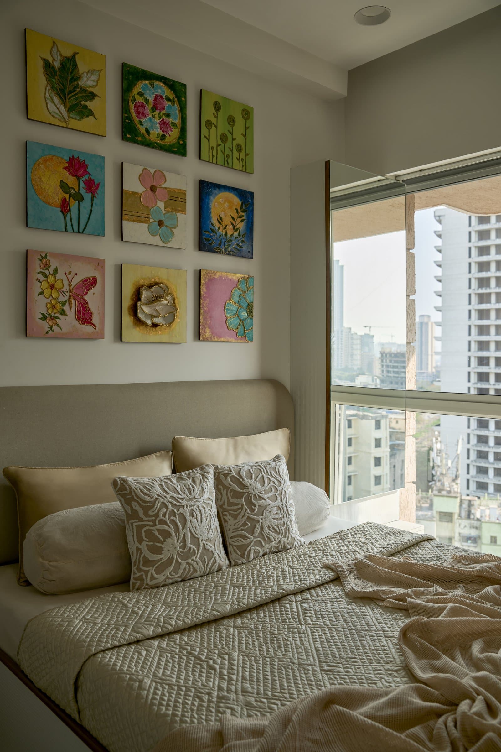 The second bedroom, where a grid of nine painted panels by the client turns the wall into a working gallery
