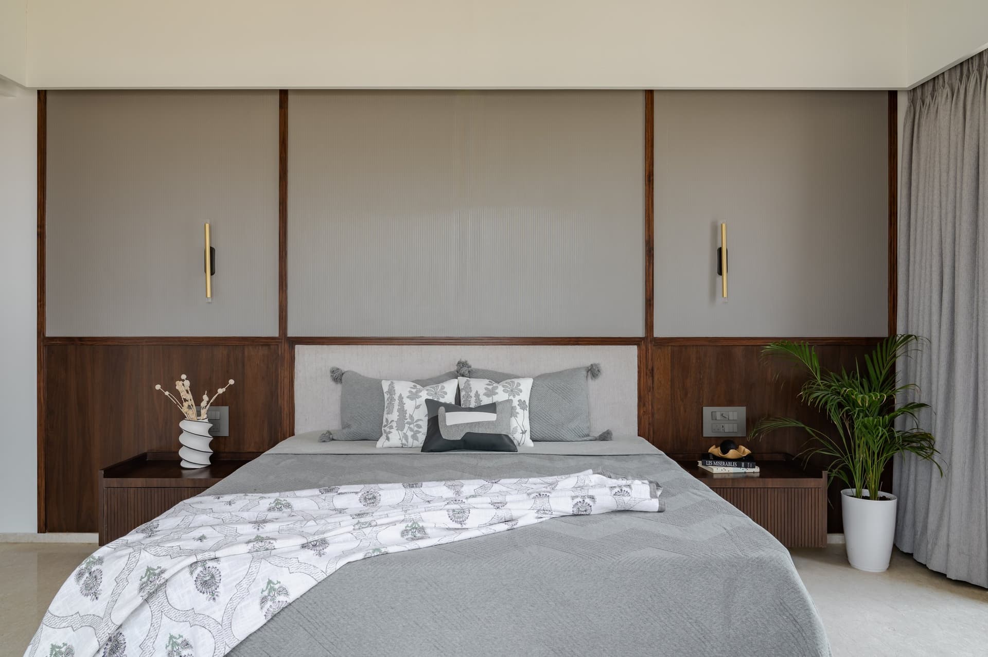 The master bedroom headboard, framed by dark walnut panels and reeded glass with brass sconces