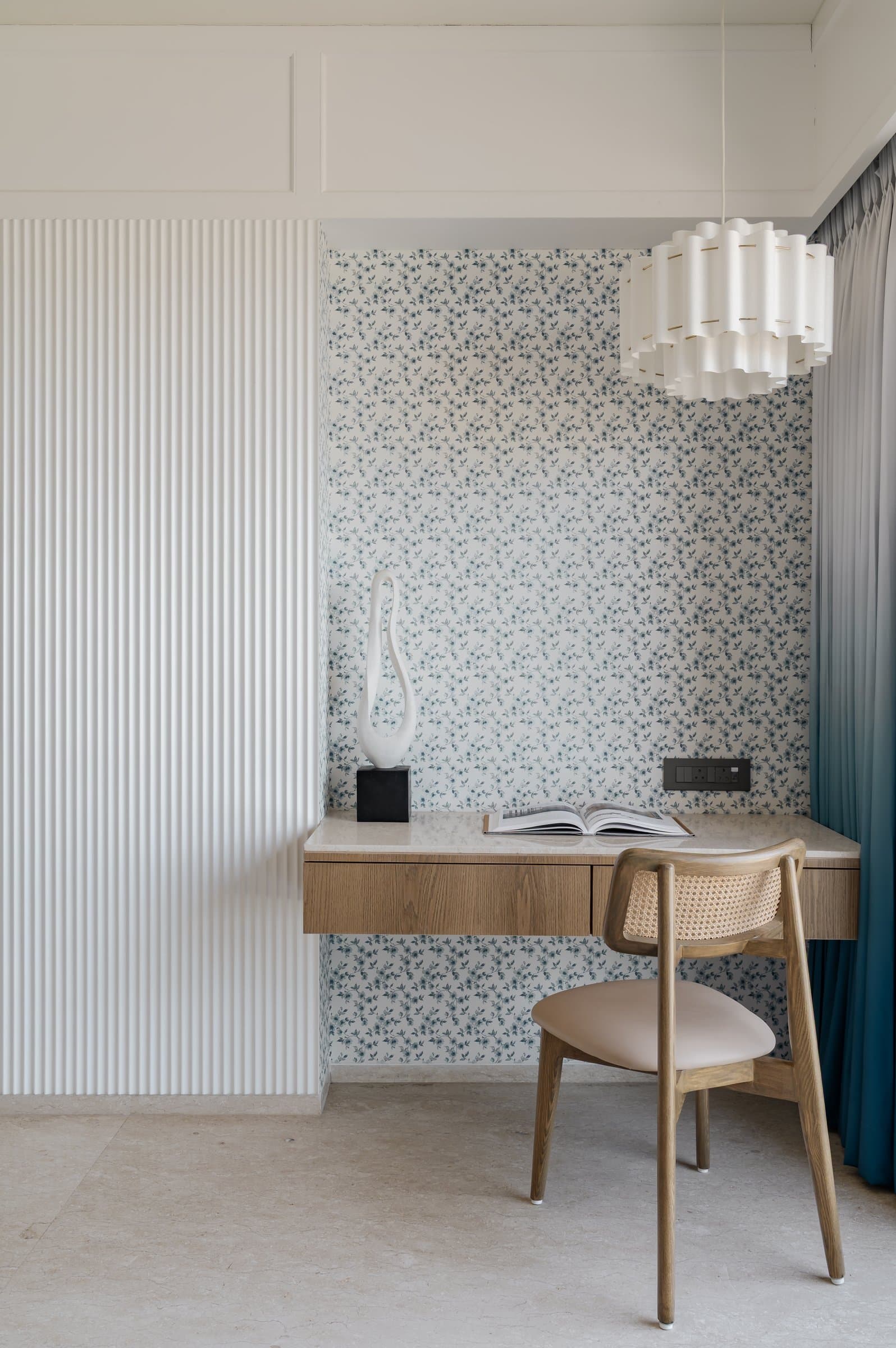 The compact study, where a floating oak desk sits against a delicate blue-and-white floral wallpaper