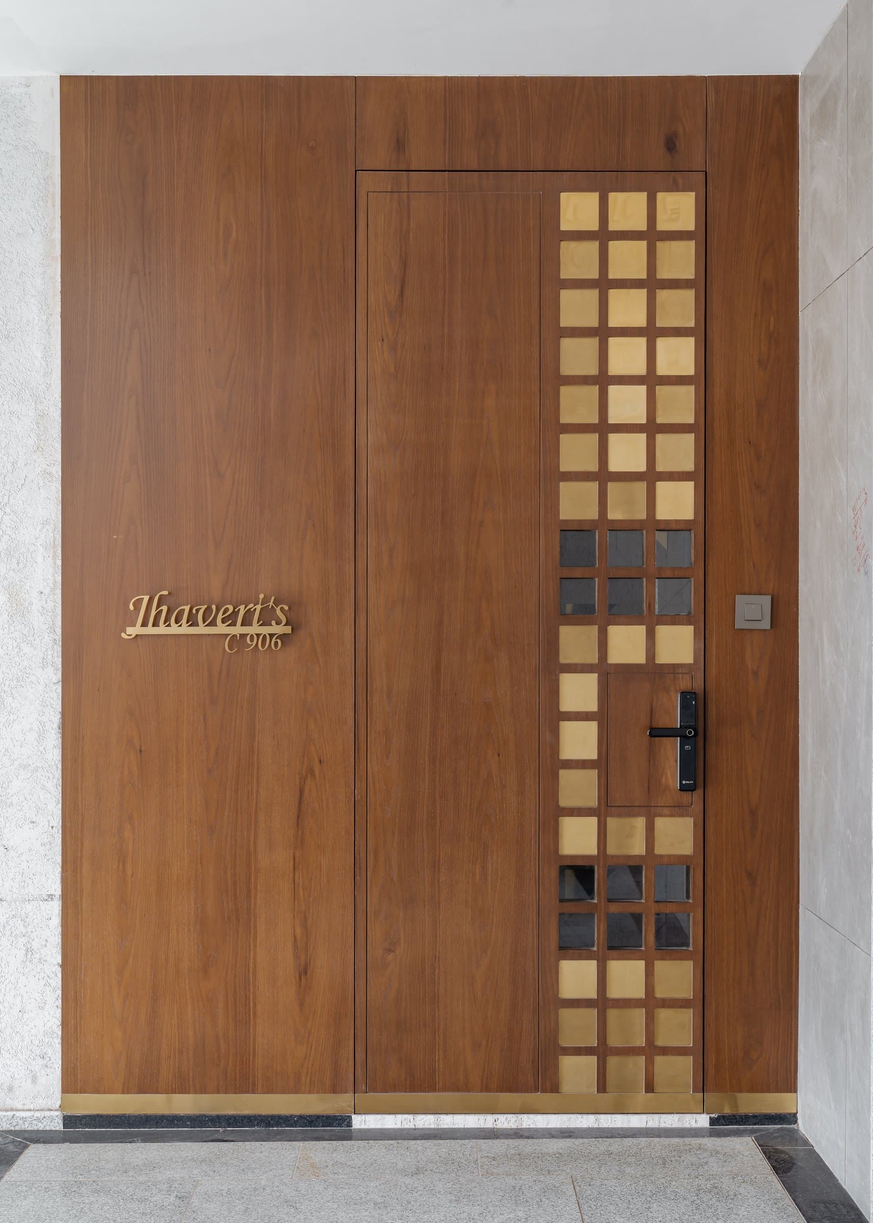 The entrance door in warm oak, inset with a grid of brass-and-glass squares beside the family nameplate